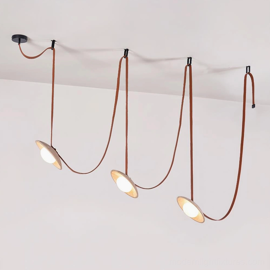 Contemporary pendant light fixture featuring dual travertine heads with leather straps, front studio perspective