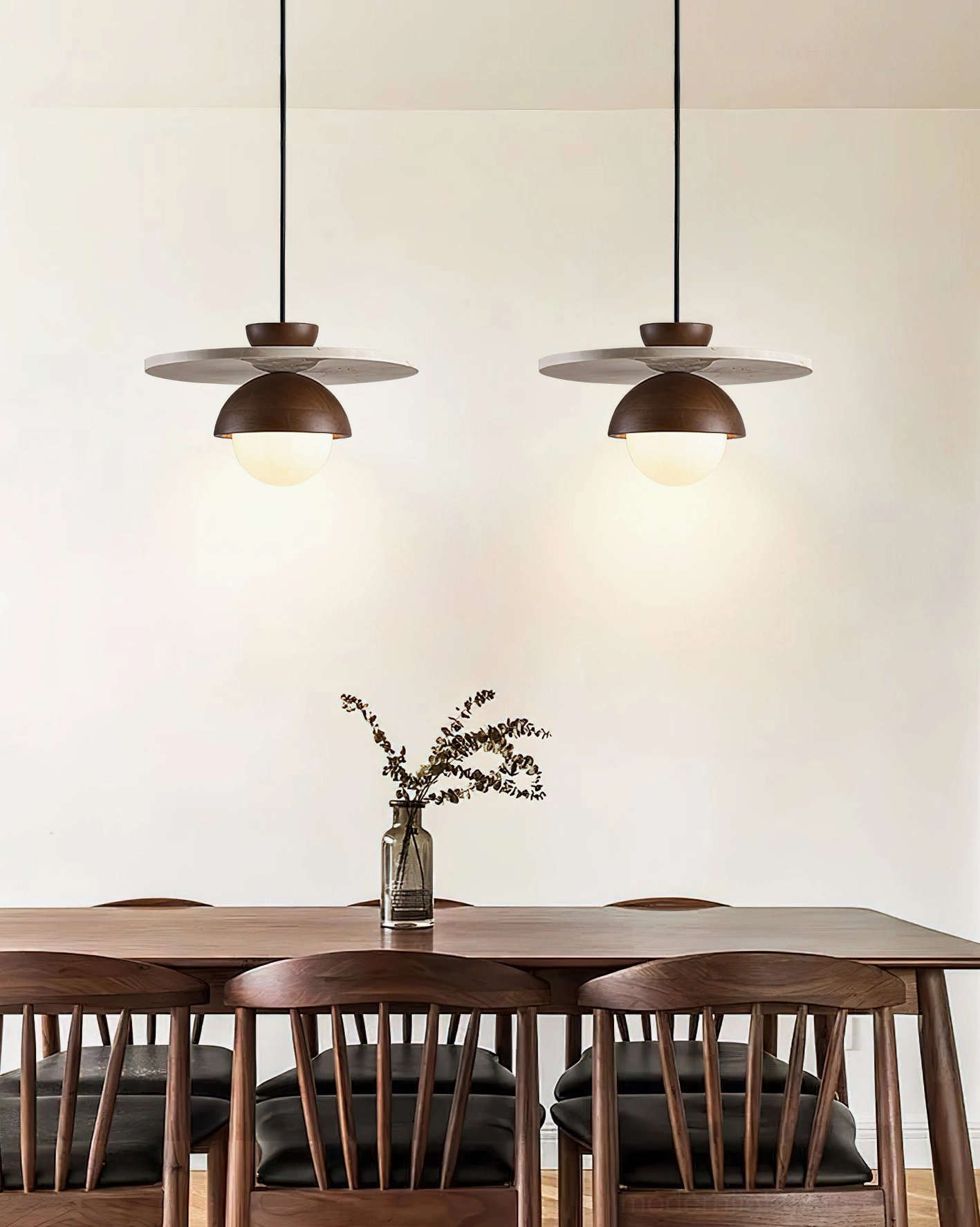 Double travertine pendant lights hanging over wooden dining table in modern dining room setting