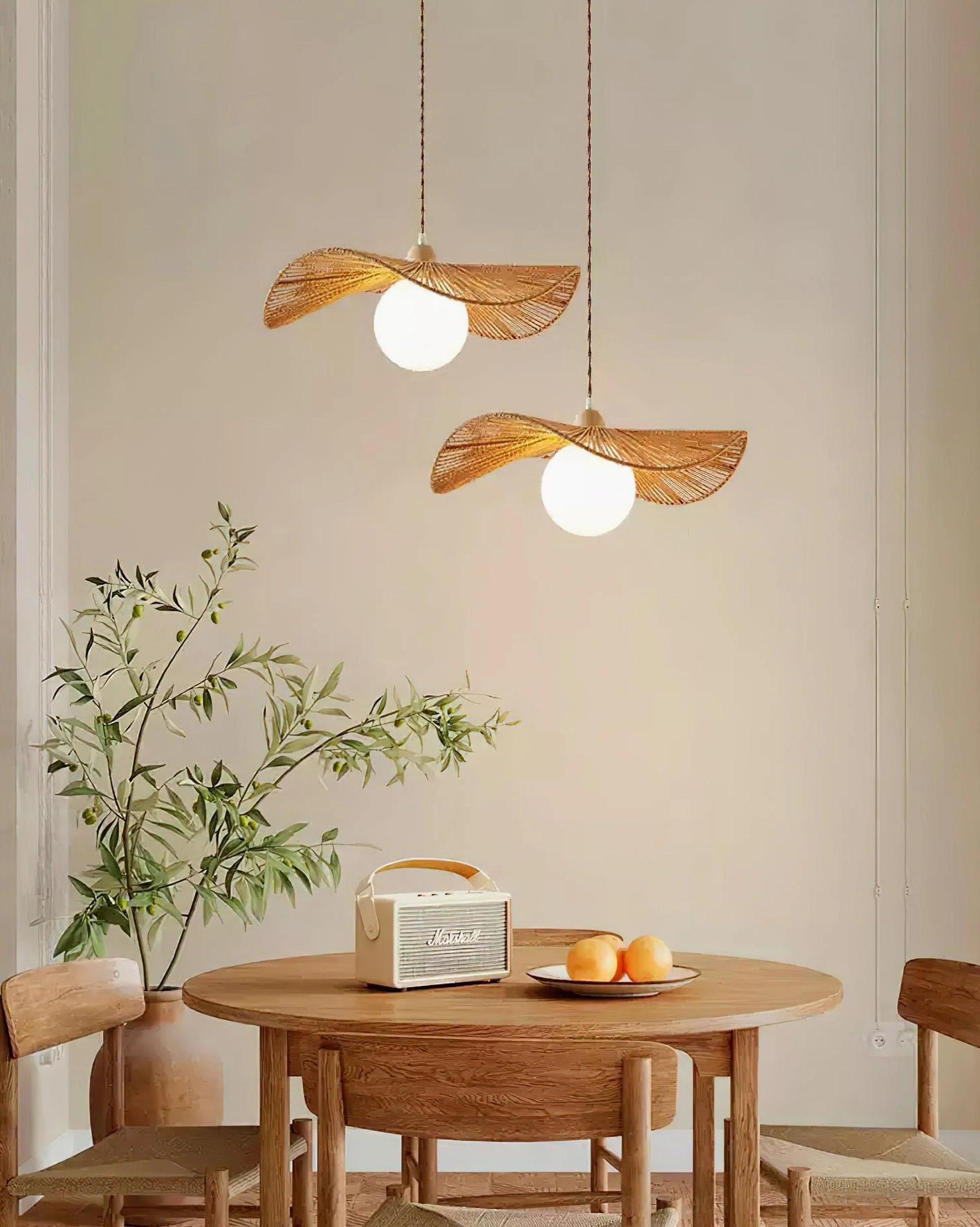 Dual woven rattan pendant lights hung above rustic wooden dining table in coastal farmhouse interior