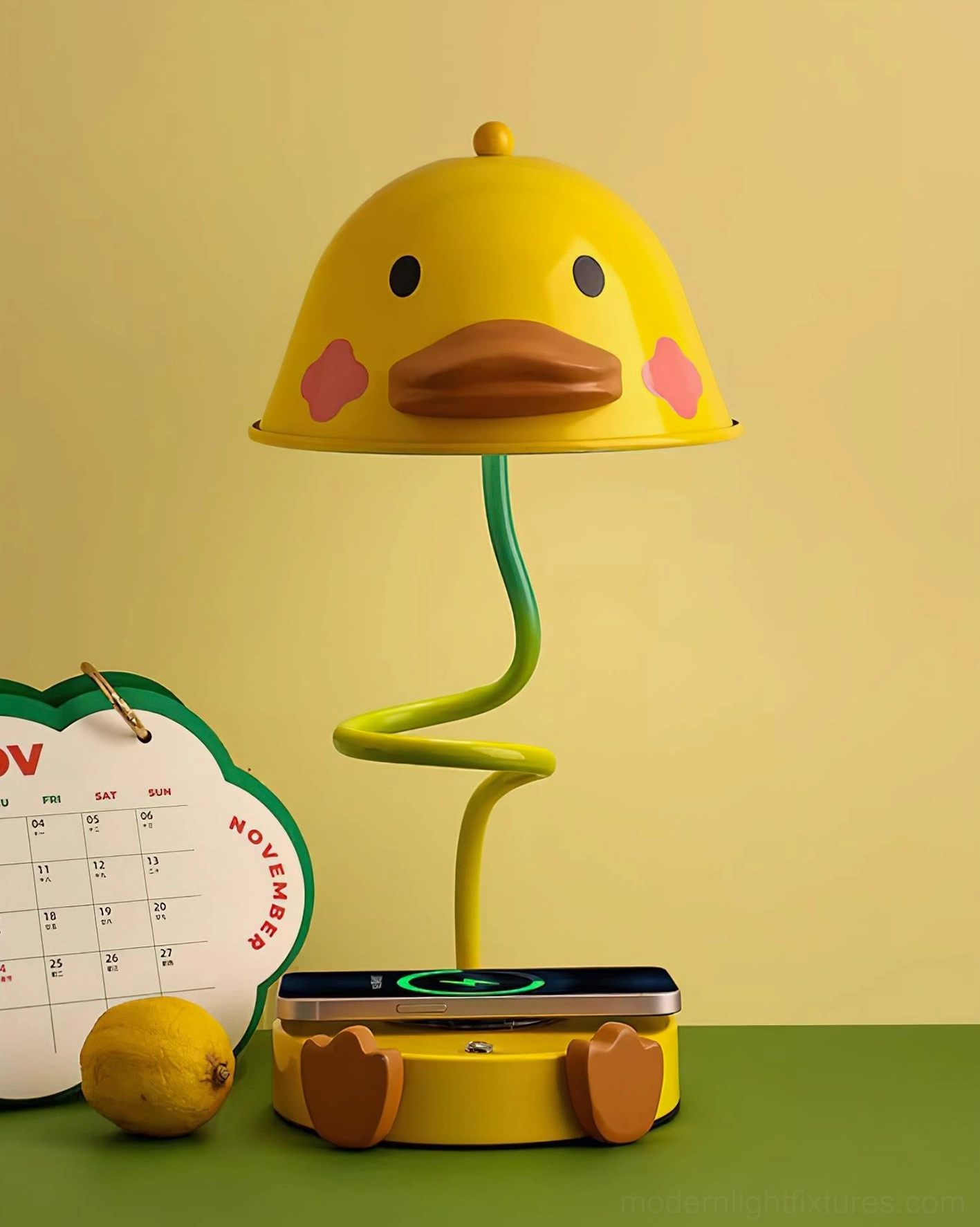 Yellow duck-shaped table lamp with three-color changing light on green tabletop with wireless charging pad