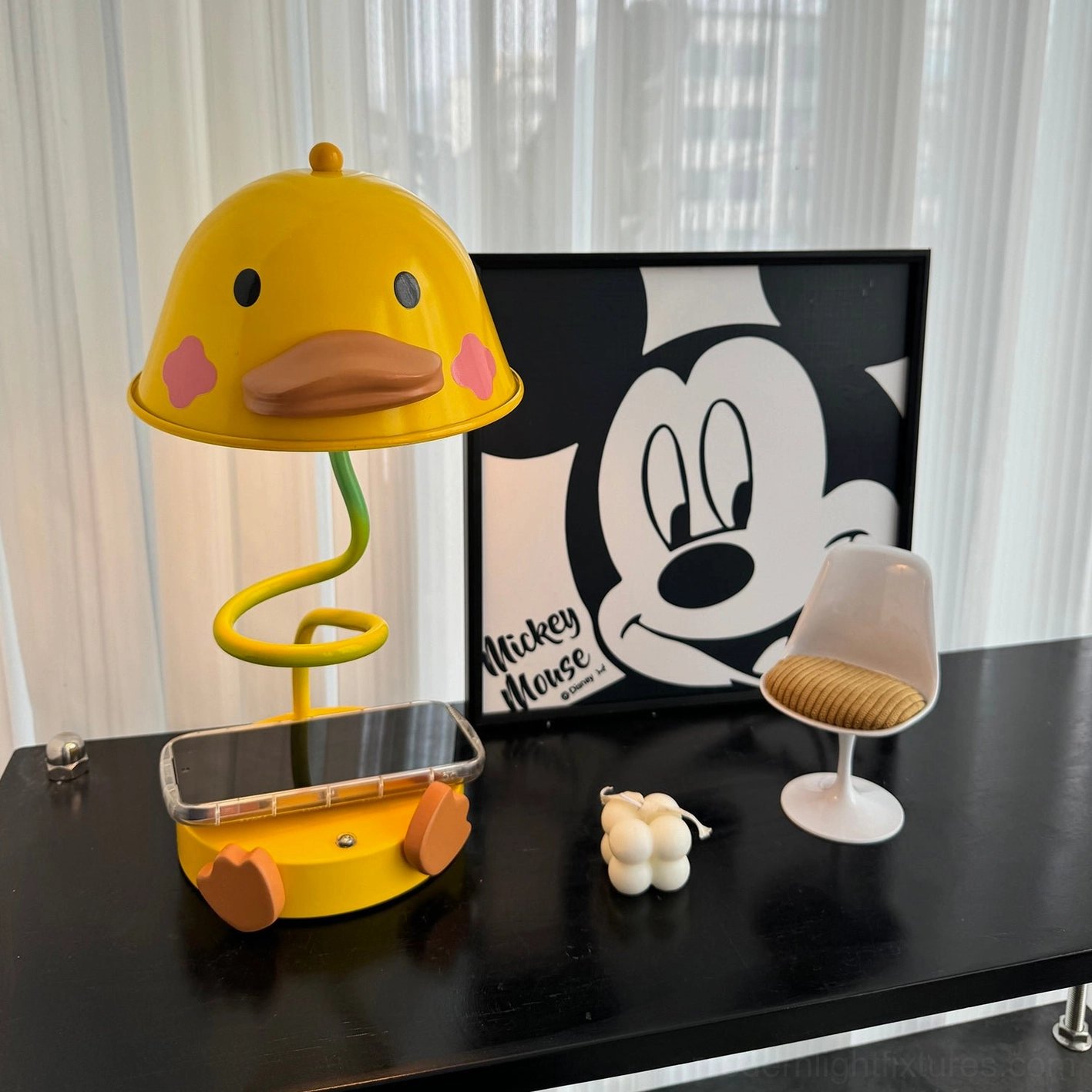 Contemporary duck table lamp with touch control on black home office desk with phone charging and artwork
