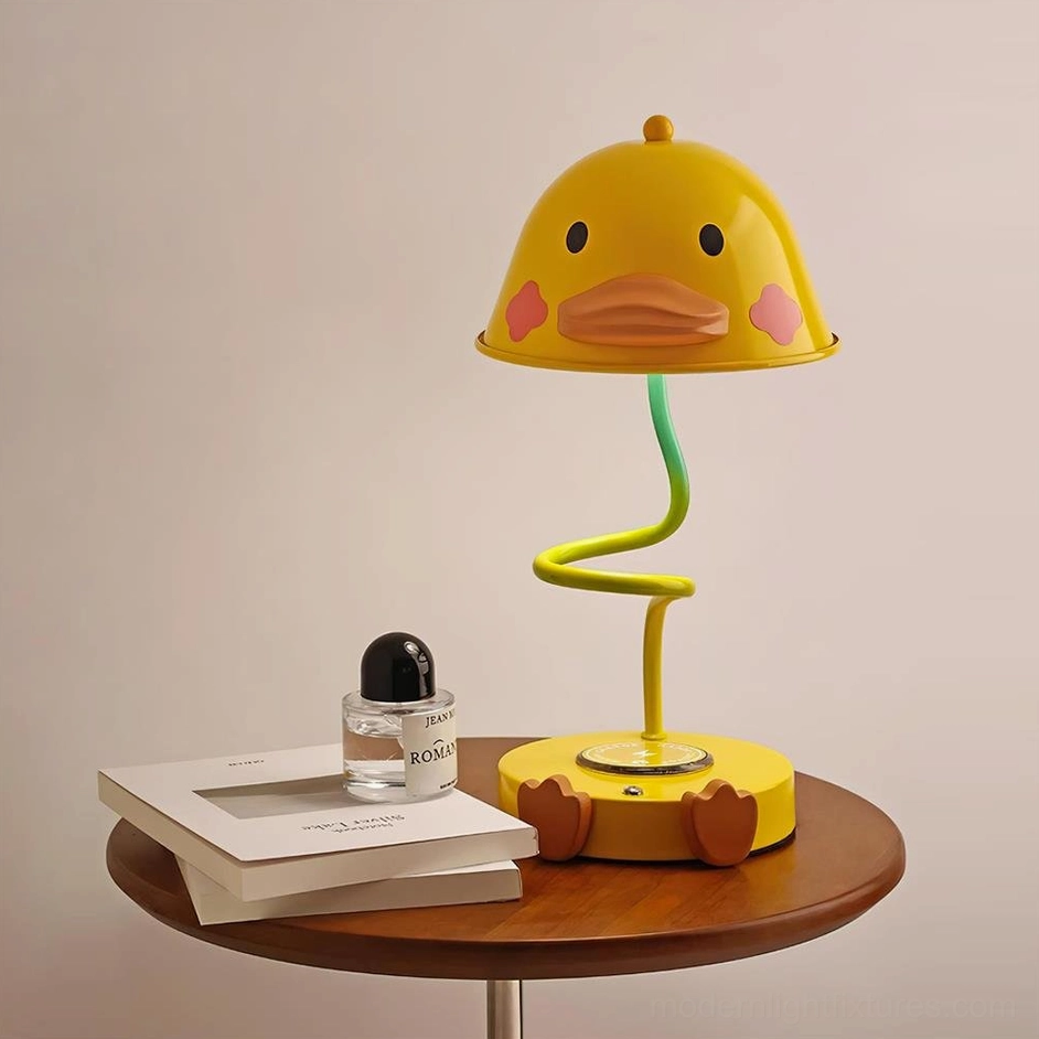 Duck design wireless charging table lamp positioned on wooden side table with decorative books and perfume bottle