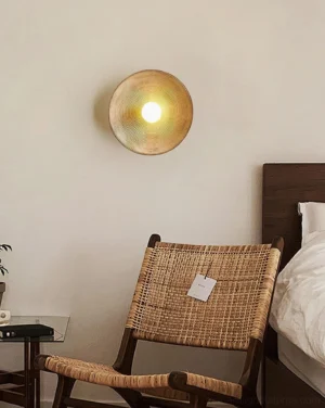 Warm gold Echo Coil circular wall lamp mounted in bedroom lounge corner at eye level, emitting soft ambient diffused lighting in modern minimalist interior