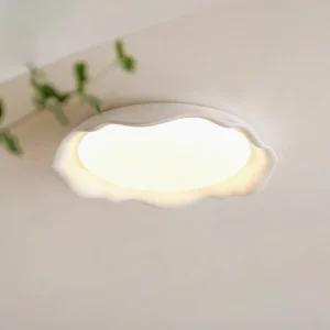 Elio modern ceiling light fixture installed in residential interior, warm white LED glow from below, near green plant foliage