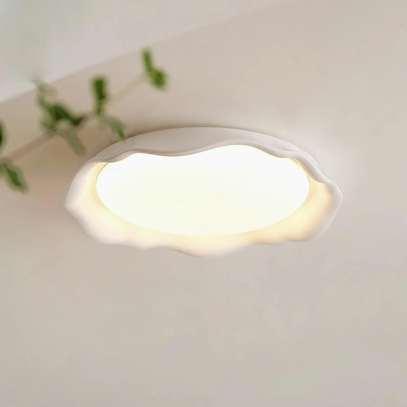 Elio modern ceiling light fixture installed in residential interior, warm white LED glow from below, near green plant foliage