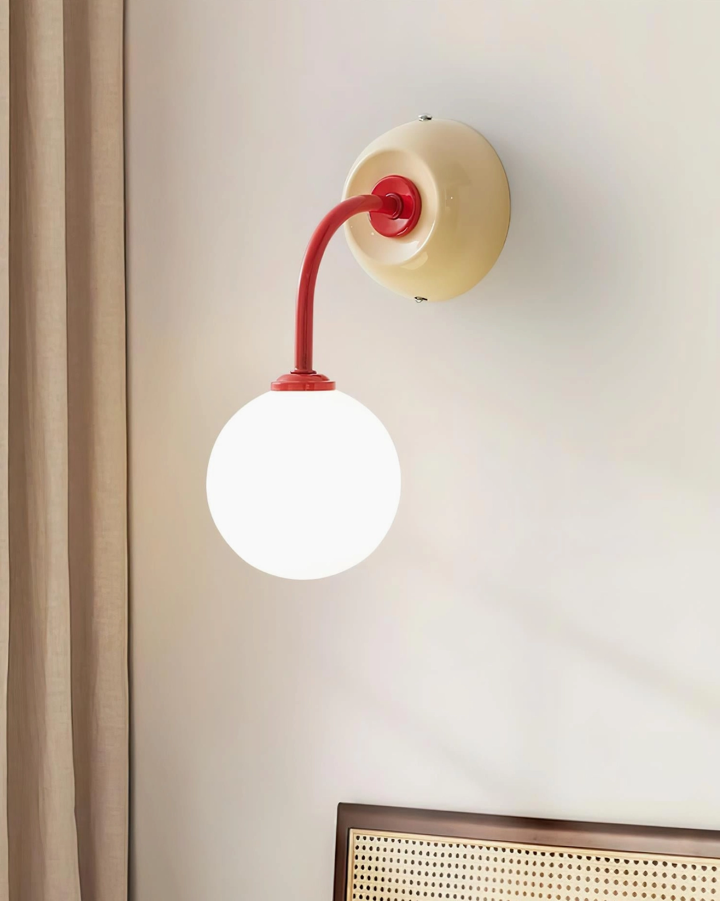 Elio wall sconce front eye-level view on residential wall with beige base and red curved arm detail