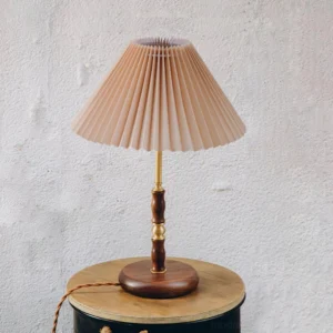 Ella pleated table lamp three-quarter view on wooden side table showing khaki pleated shade and brass accents