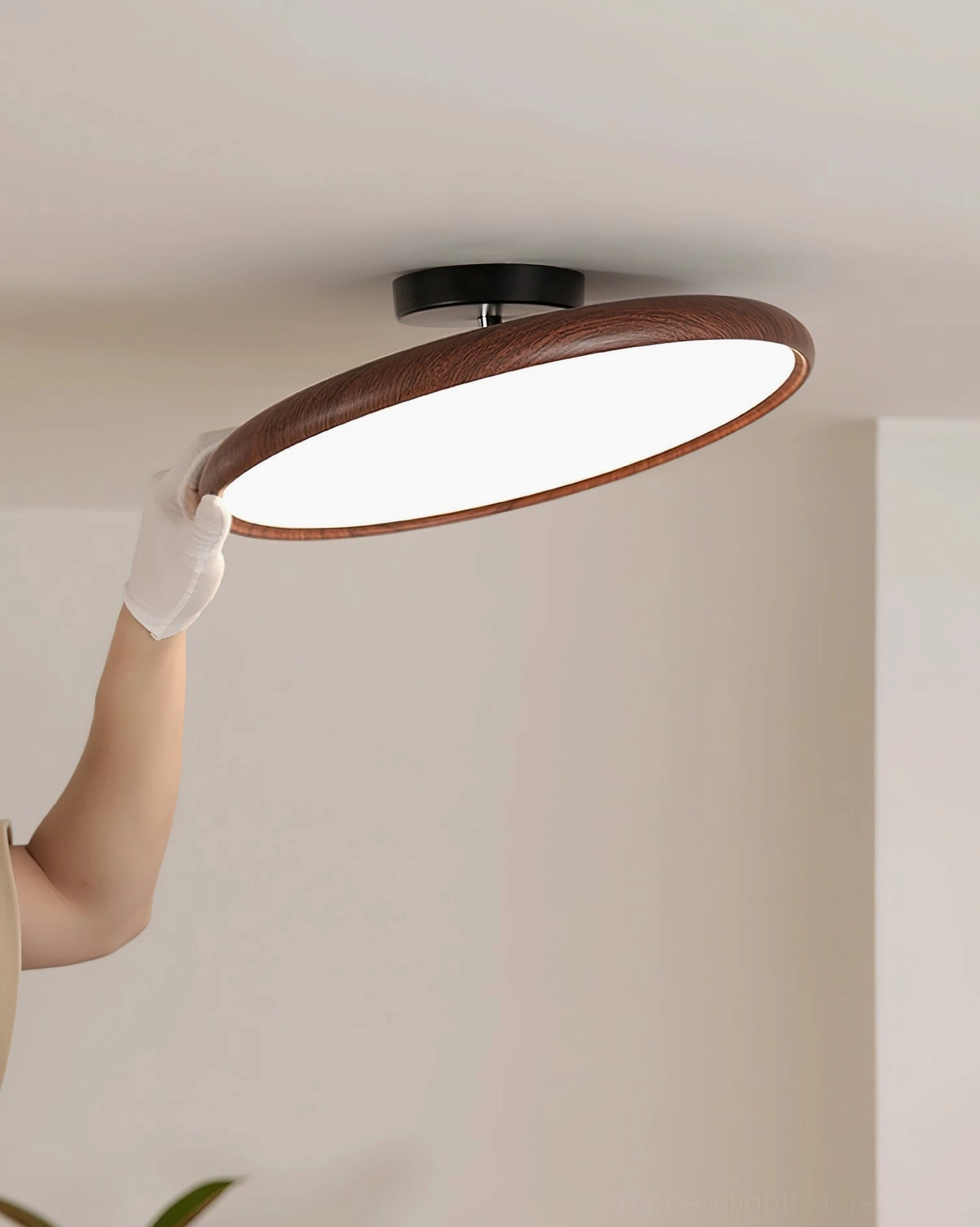 Ellos ceiling light being held by hand showing slim 12cm profile and wood-grain texture