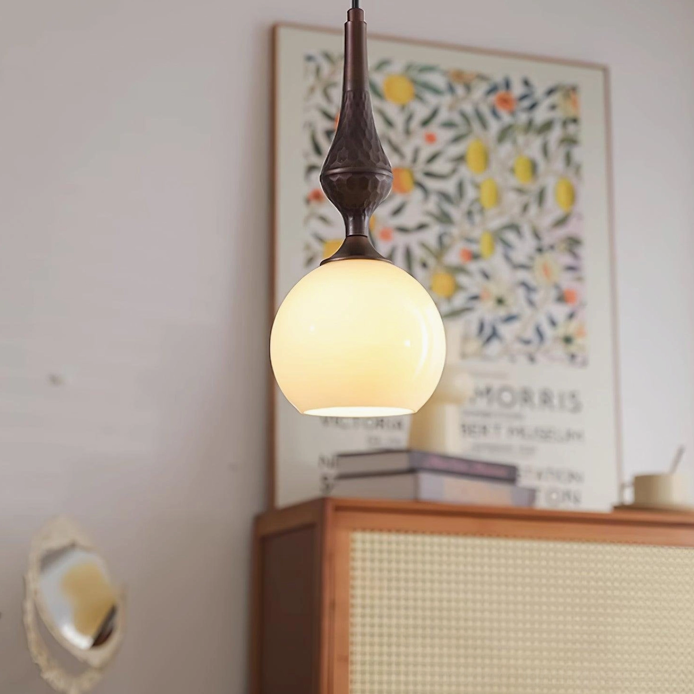 Dark brown metal stem with white glass shade pendant light styled in residential interior space