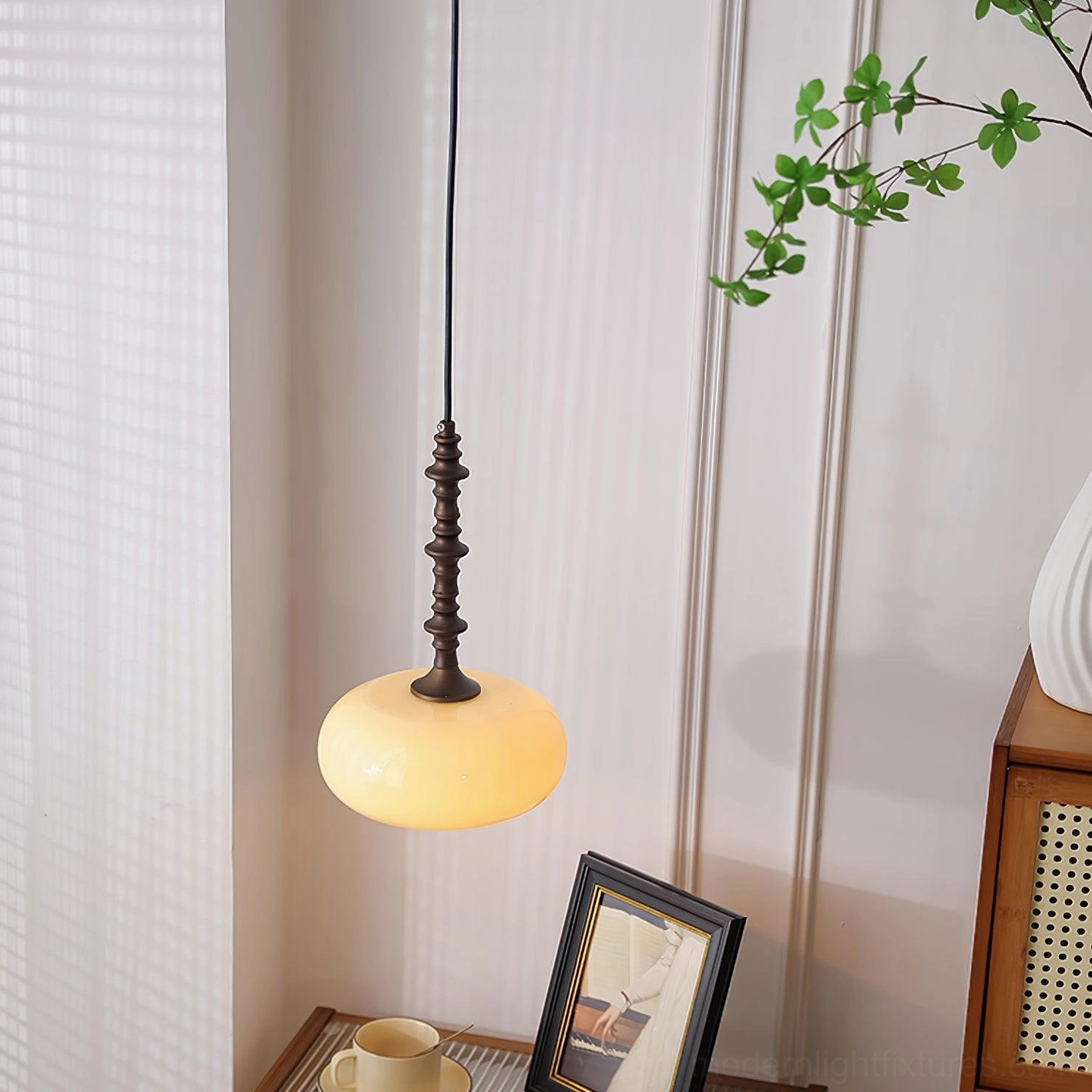 Eloise pendant lamp side view showing cream glass diffuser and sculptural metal armature in home setting
