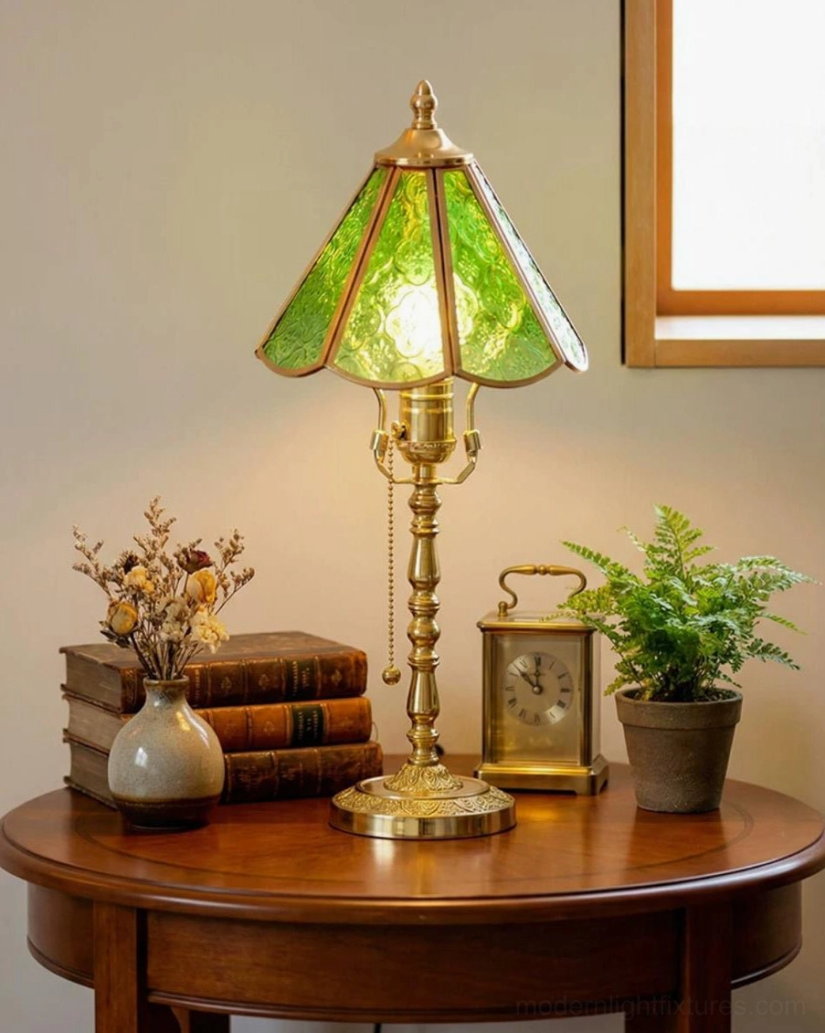 Elowen brass and green glass table lamp on round side table with vintage clock and dried flowers
