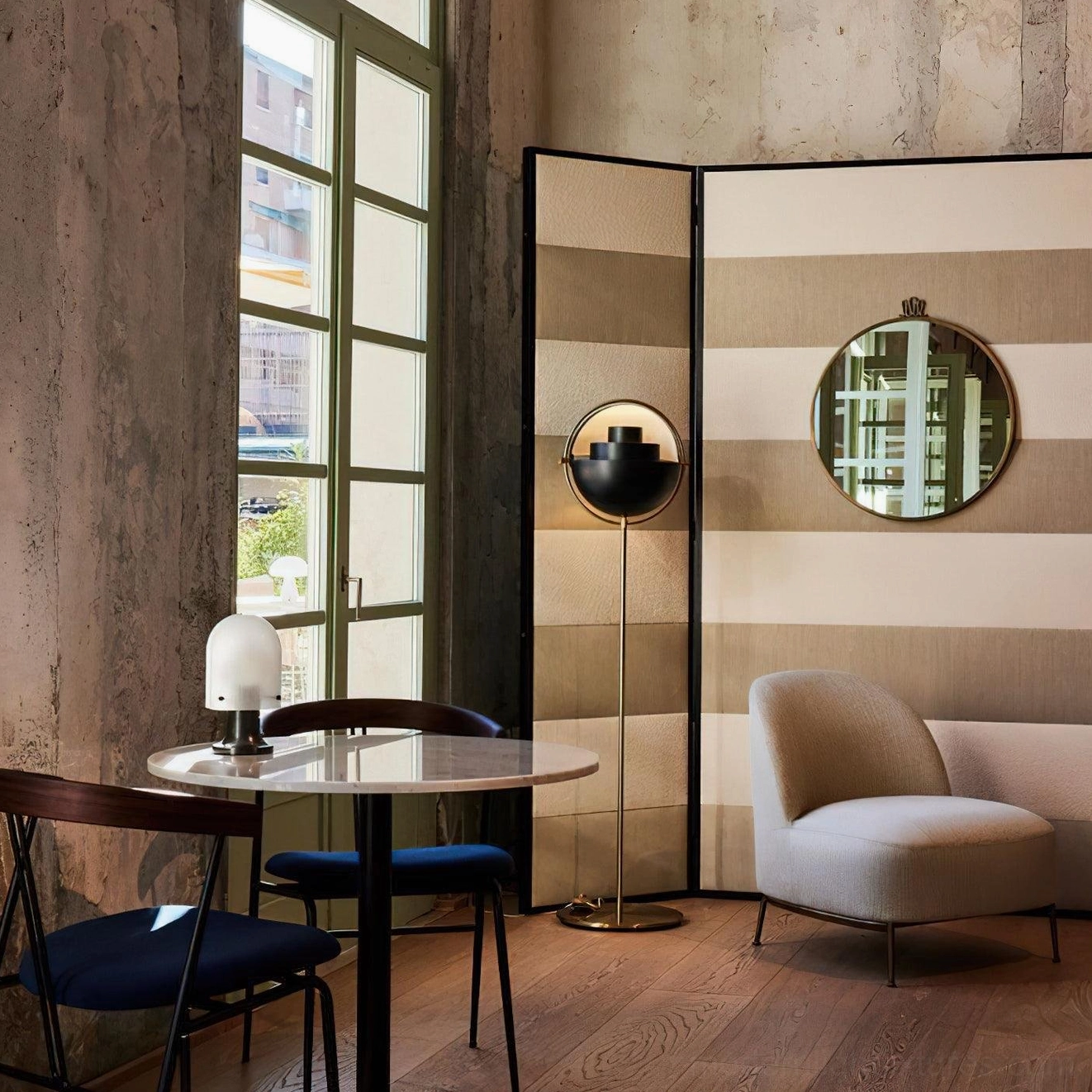 Black spherical Elvira floor lamp with brass pole positioned beside round dining table in vintage lounge setting