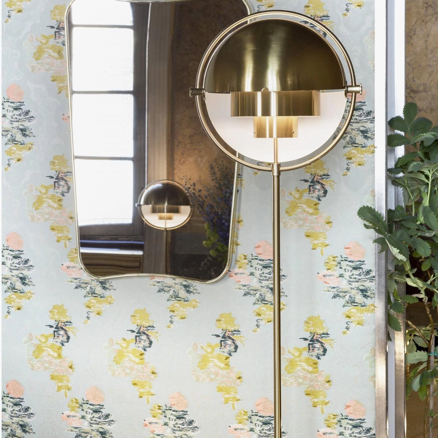 Brass spherical Elvira floor lamp with gold half-round lamp shade close-up in vanity area with floral wallpaper