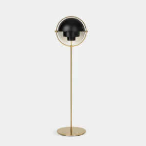 Modern Elvira floor lamp with semi-spherical design, brass gold metal pole and half-black lamp shade in minimalist studio setting