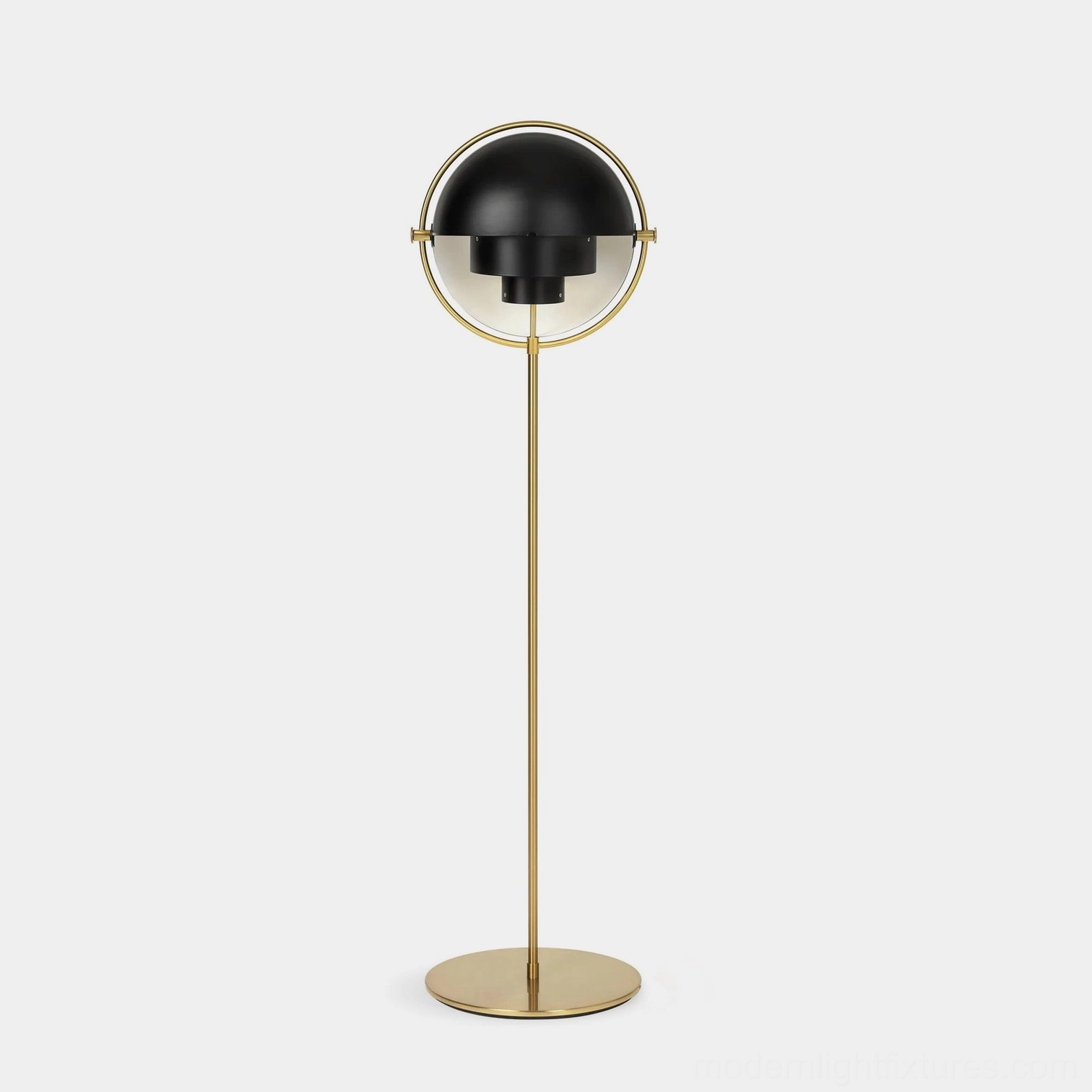 Modern Elvira floor lamp with semi-spherical design, brass gold metal pole and half-black lamp shade in minimalist studio setting