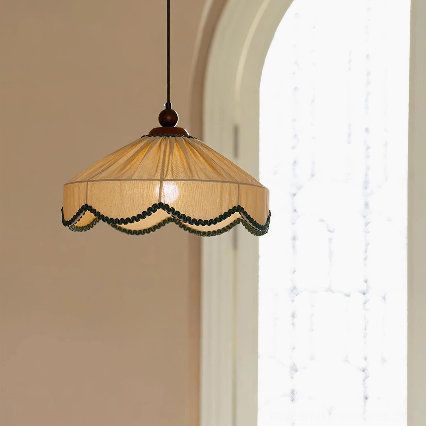 Elysia pendant lamp close-up in residential setting with arched window, showing tan linen shade and glowing bulb detail