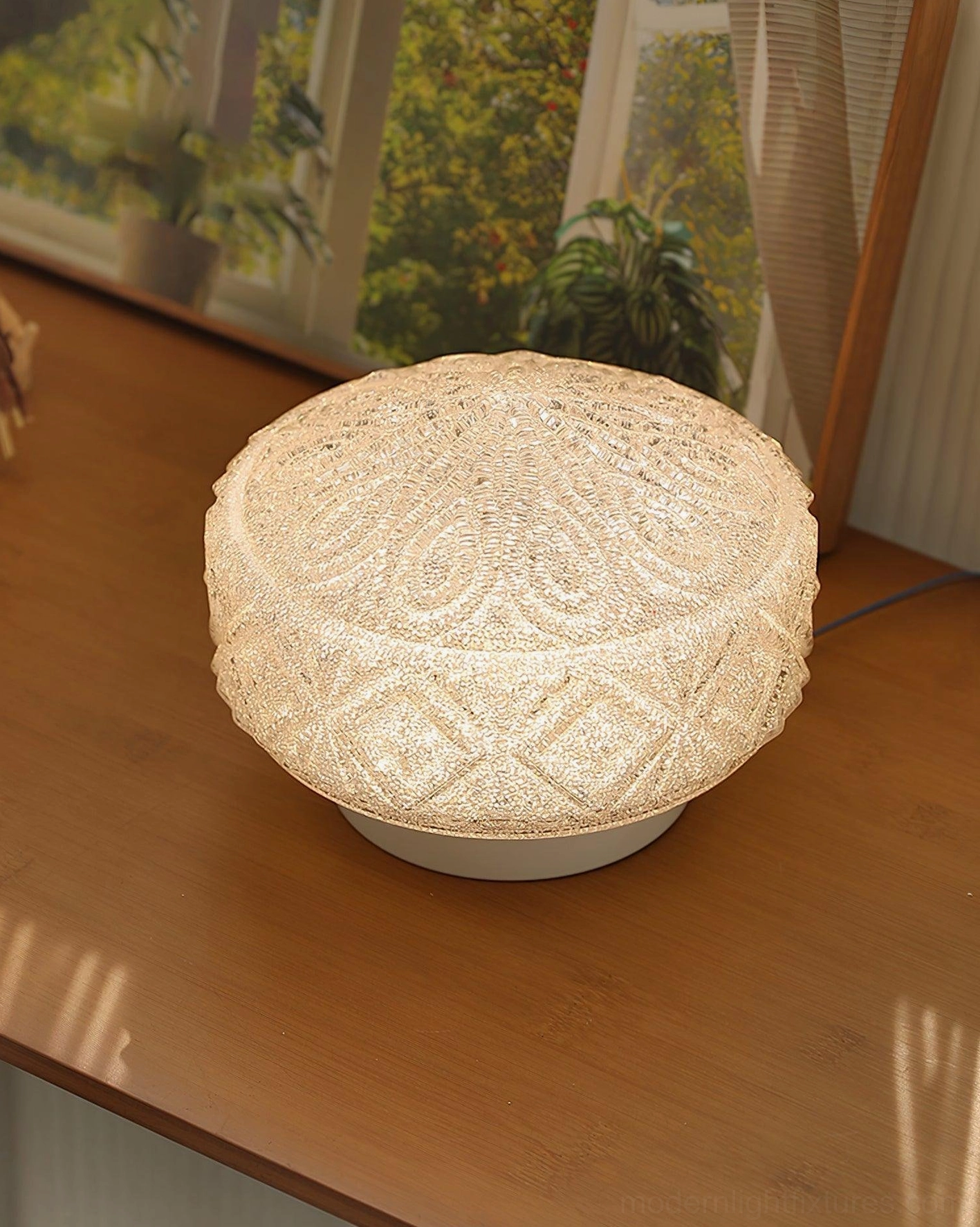 Decorative carved glass ceiling light with glittery cream finish and matching embossed patterns, tabletop display with window backdrop