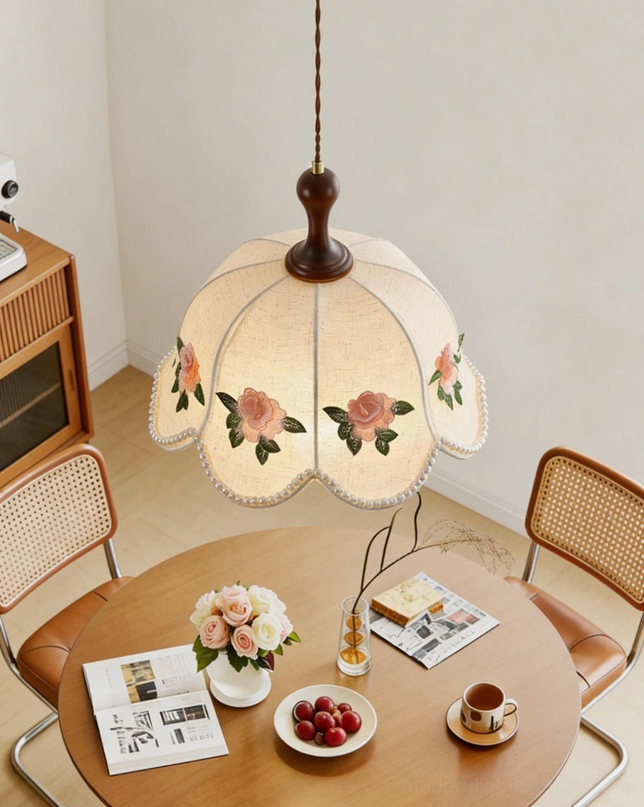 Embroidered rose pendant light with walnut wood stem and twisted cord, hanging over wooden dining table in cottagecore interior