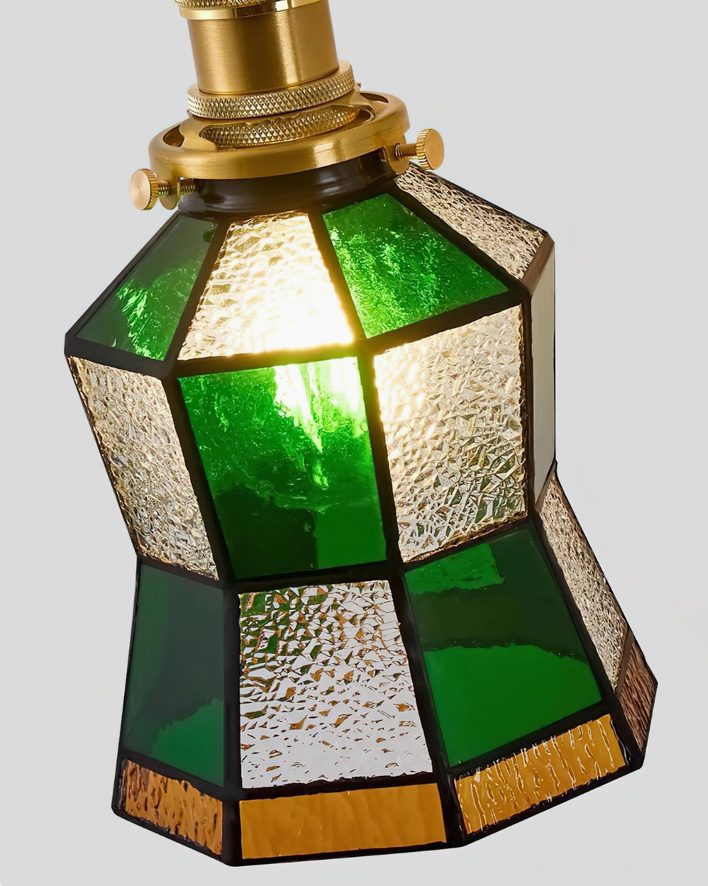 Emerald and brass vintage stained glass wall sconce color variation detail showing warm amber and green glass panel interplay