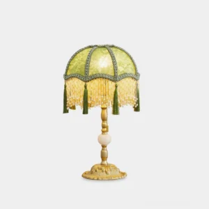 Emerald green velvet table lamp with gold base and beaded tassels front view on white background