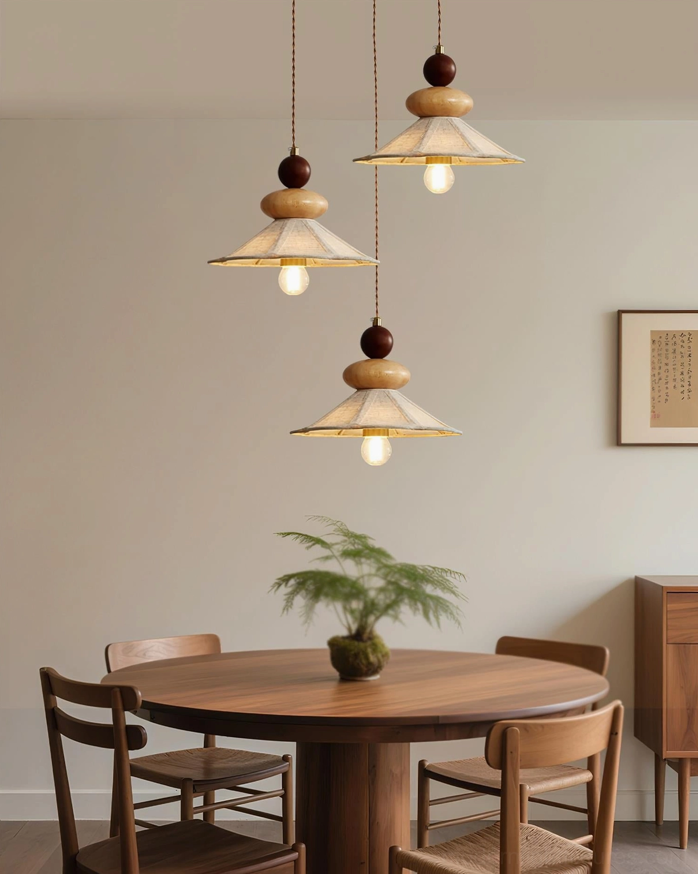 Three matching wooden pendant lights suspended over round dining table, rustic trio creating elegant warm dining room atmosphere