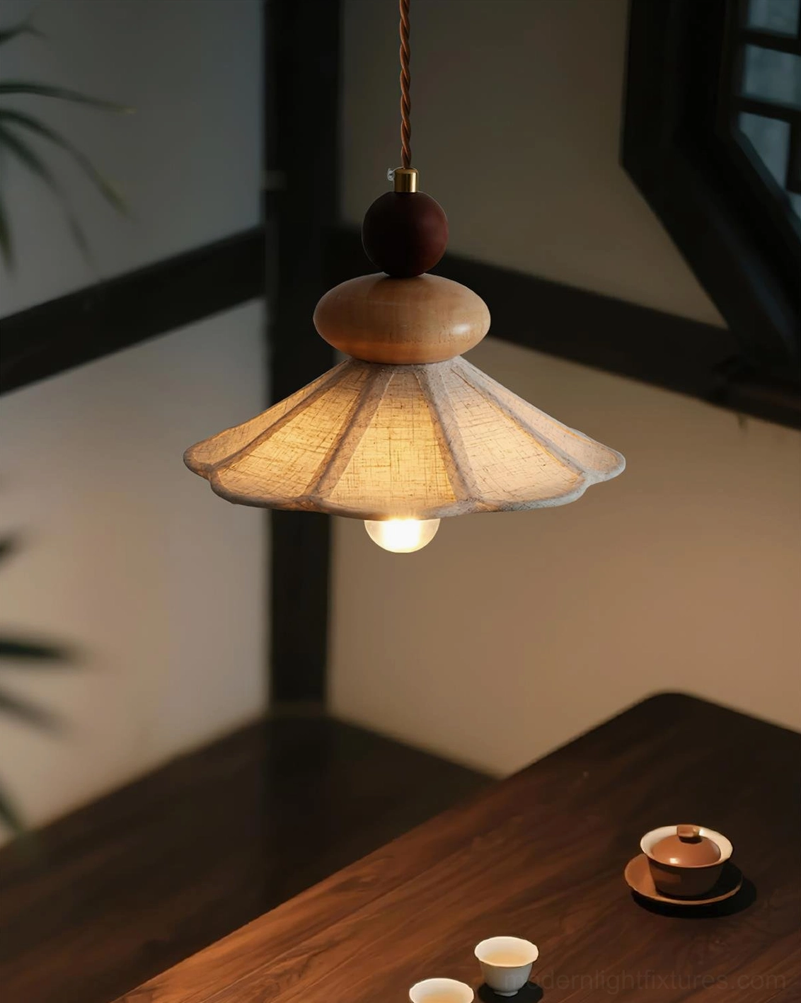 Warm wooden pendant lamp hanging above traditional tea set in Asian interior, ambient lighting with beige fabric shade