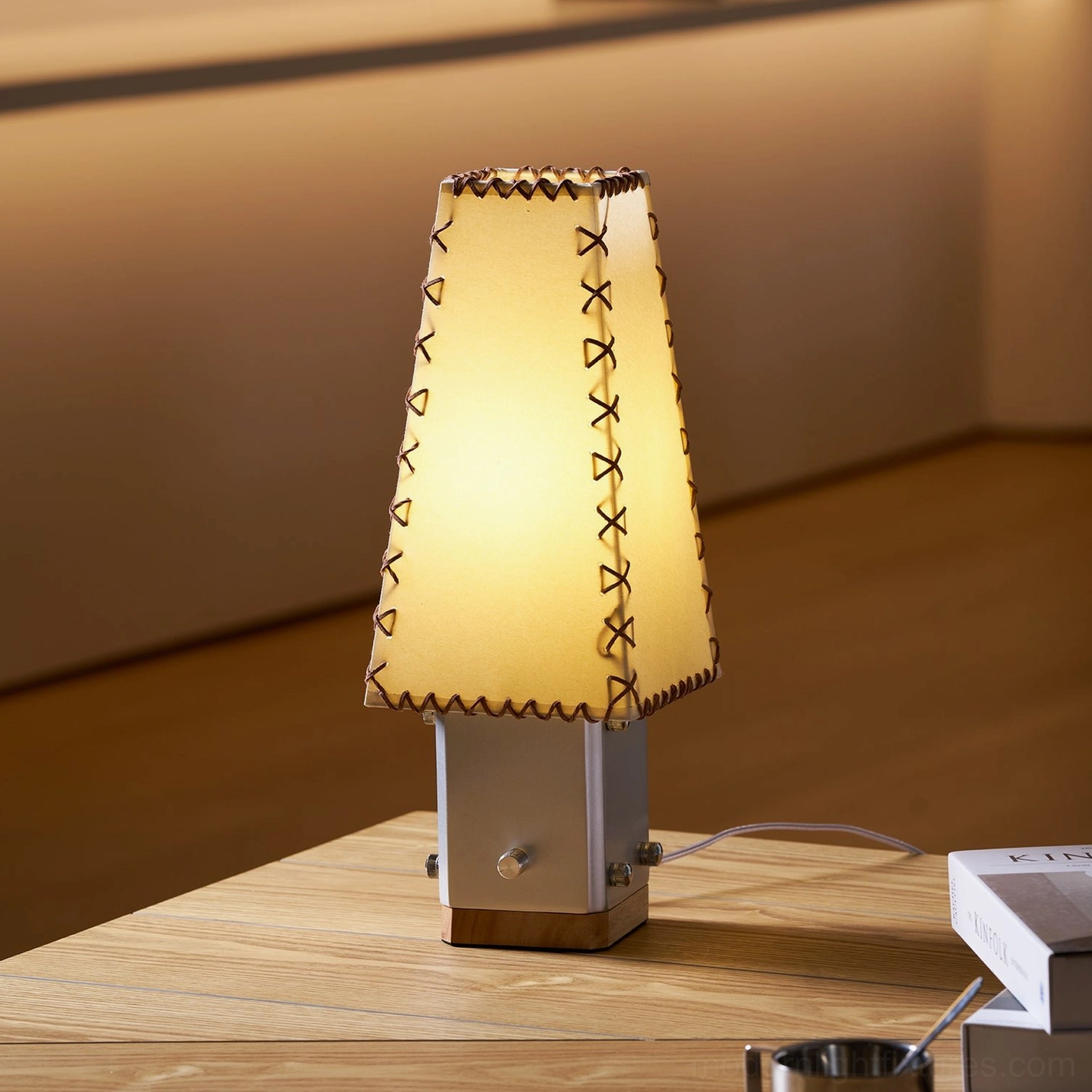 Estela table lamp illuminated on wooden table in warm indoor setting with ambient lighting