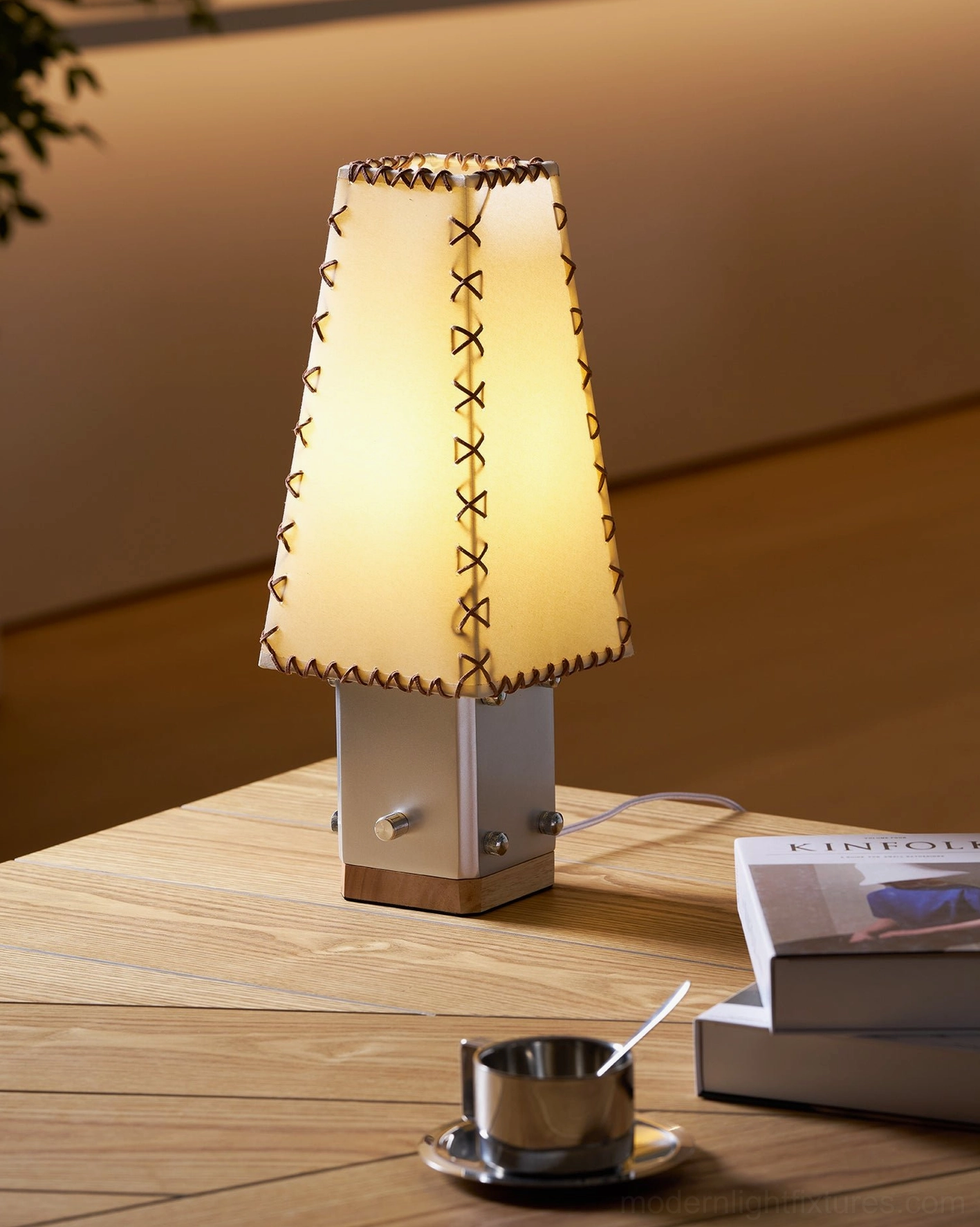 Estela table lamp side view with stacked books and metal cup on wooden side table