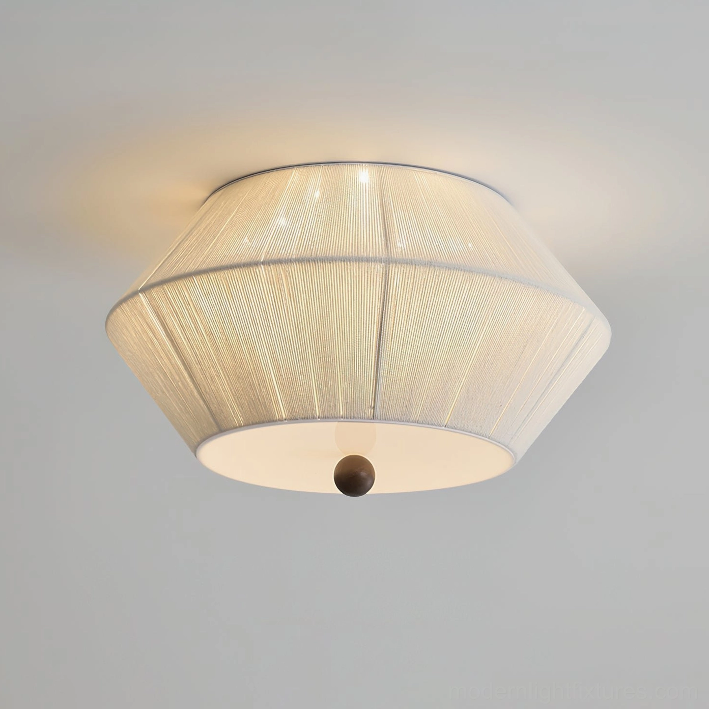 Close-up of tapered fabric drum shade showing vertical pleats and warm illuminated glow with dark bottom accent detail