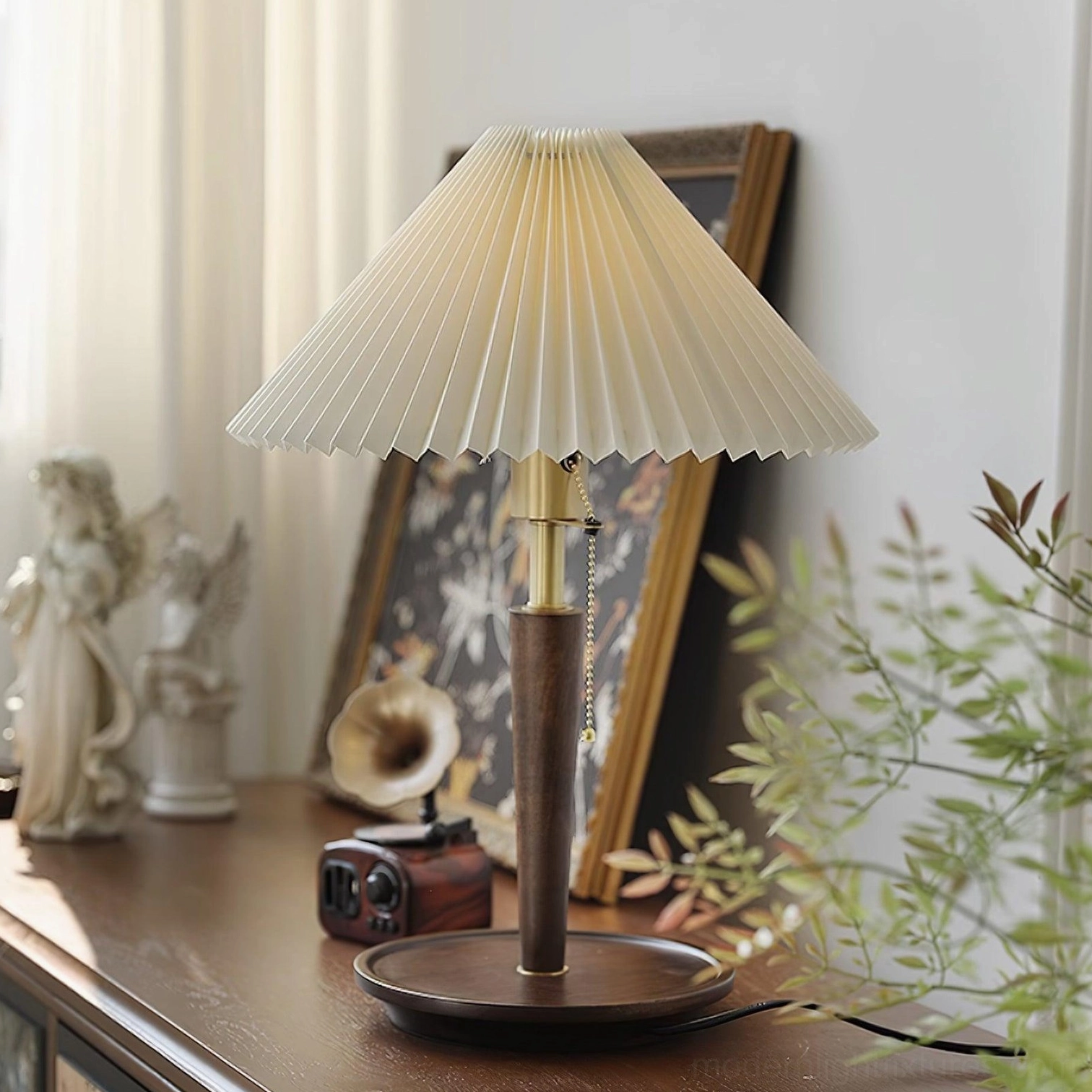 Pleated fabric table lamp with pull-chain switch and solid wood base on wooden table with vintage greenery decor