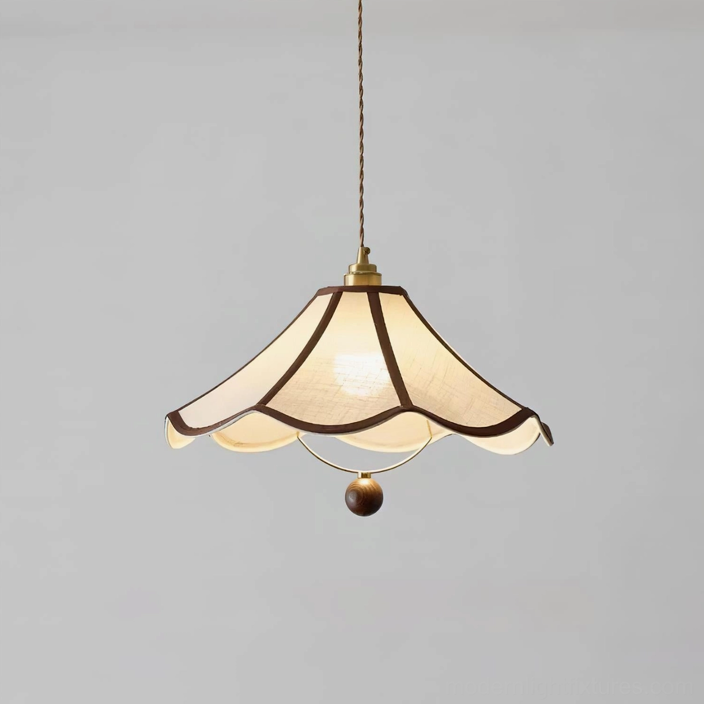 Three-quarter view of fabric scalloped pendant light showing illuminated shade detail