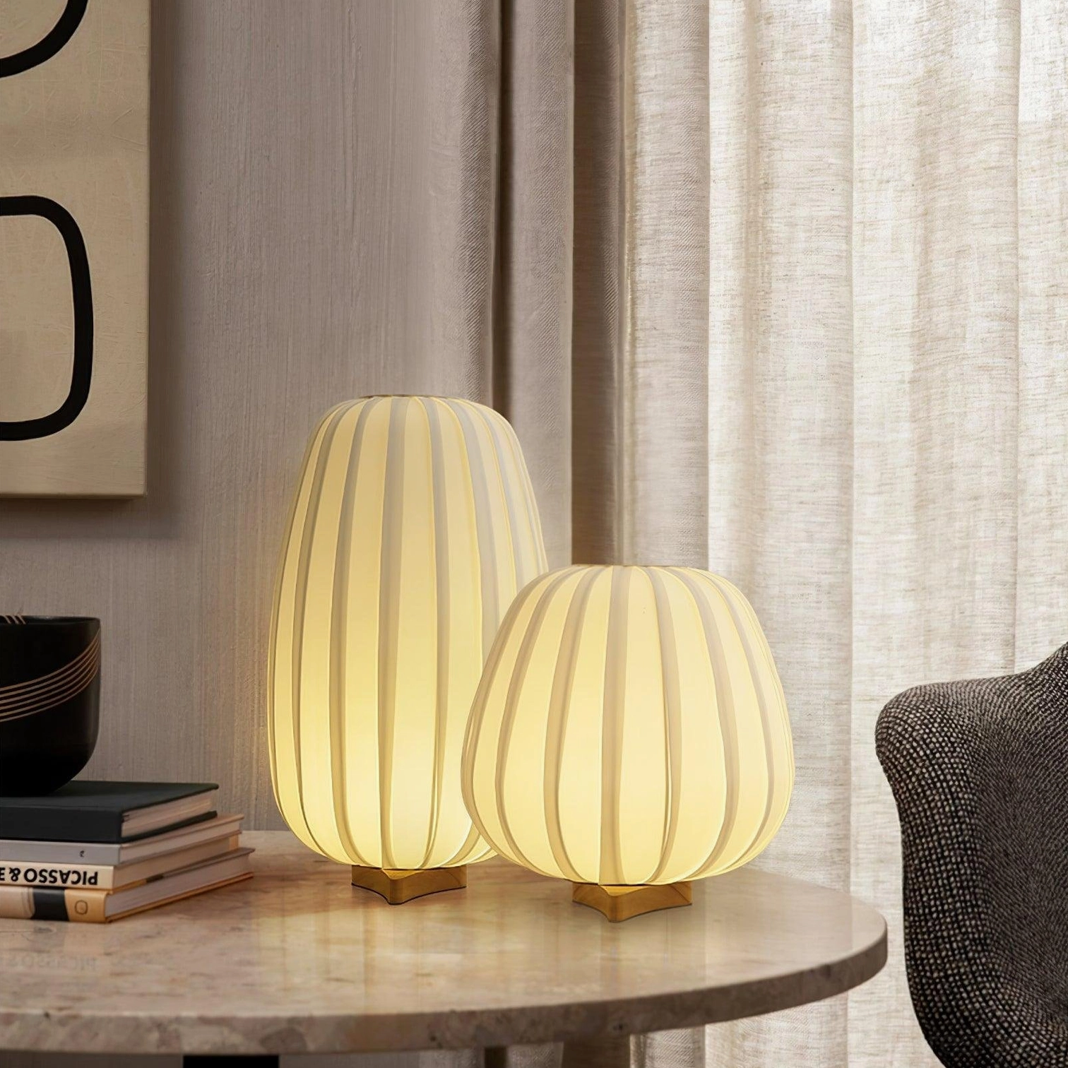Modern fabric table lamp placed on marble side table with stacked books and contemporary decor