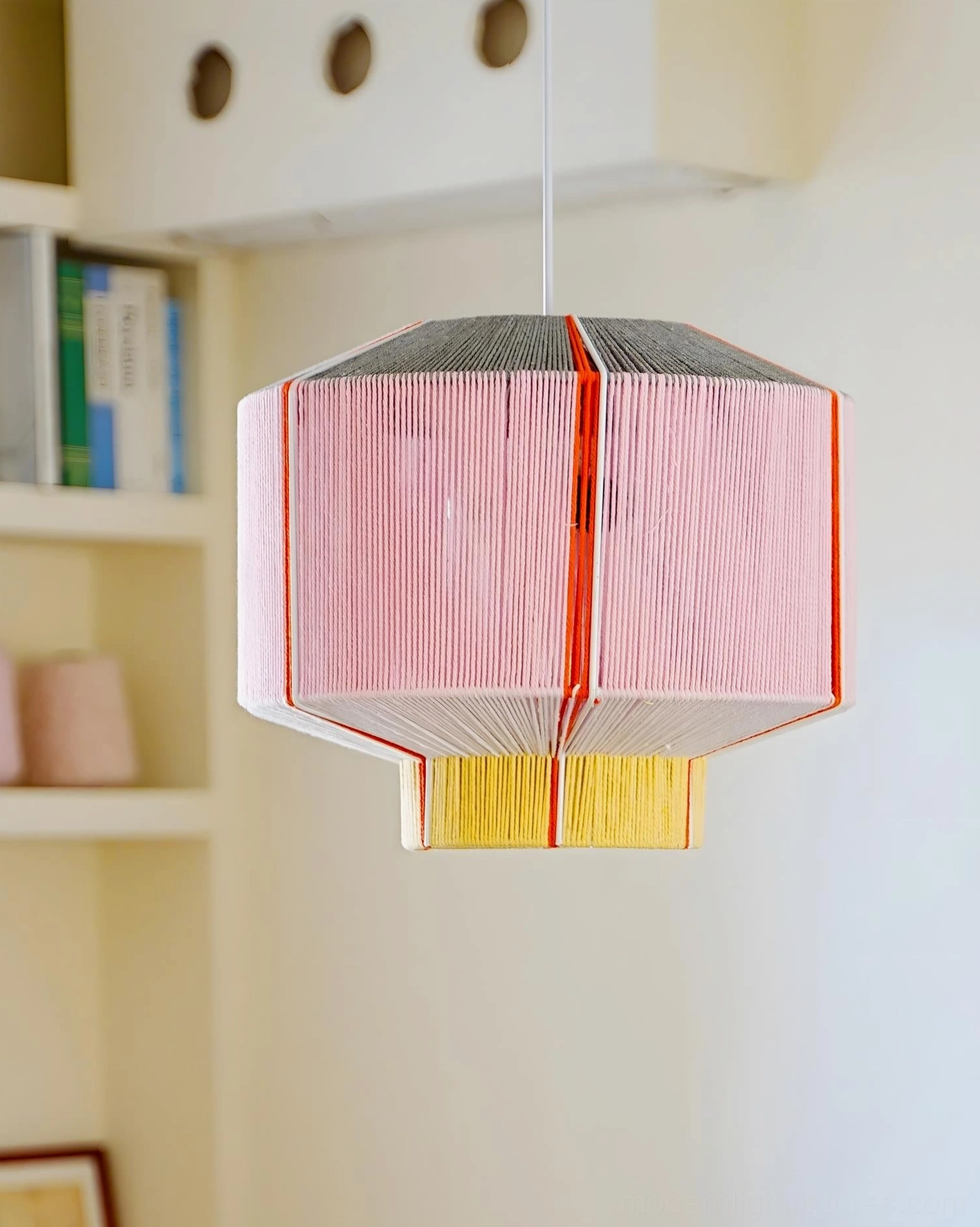 Geometric faceted pendant lamp hanging from adjustable cord above dining table in eclectic interior