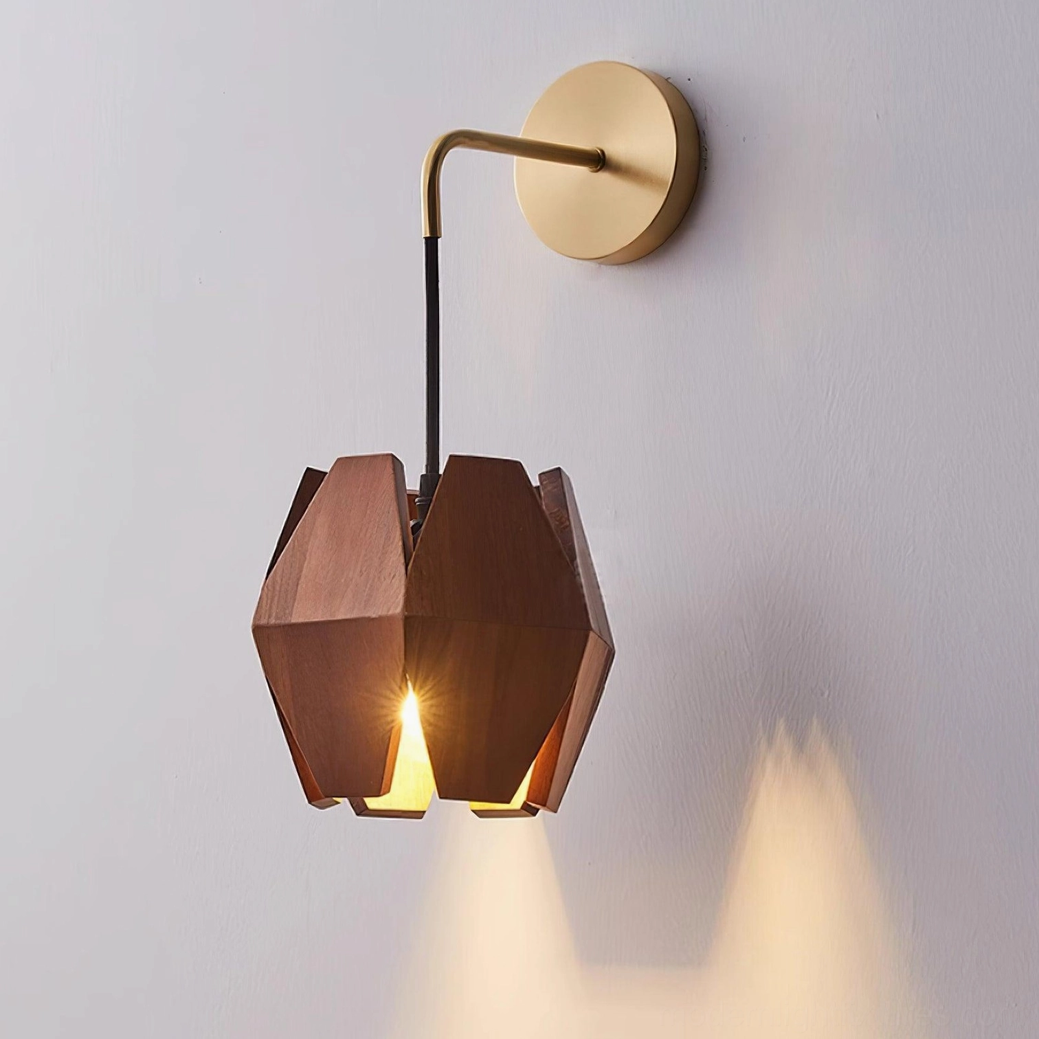 Modern faceted wood wall sconce casting directional light downward on gray wall backdrop