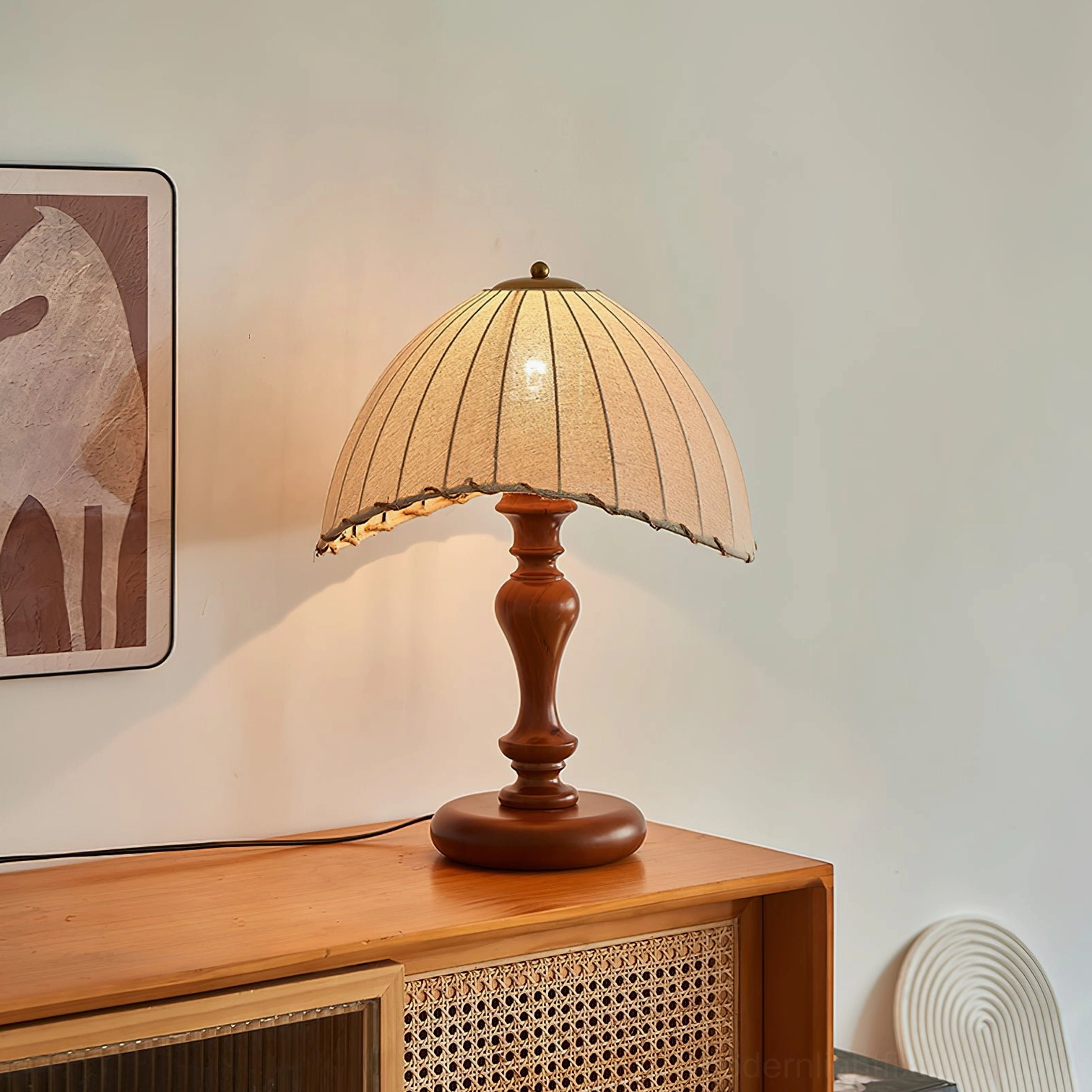 Farmhouse style table lamp glowing in living room setting with vintage wall art, three-quarter front angle