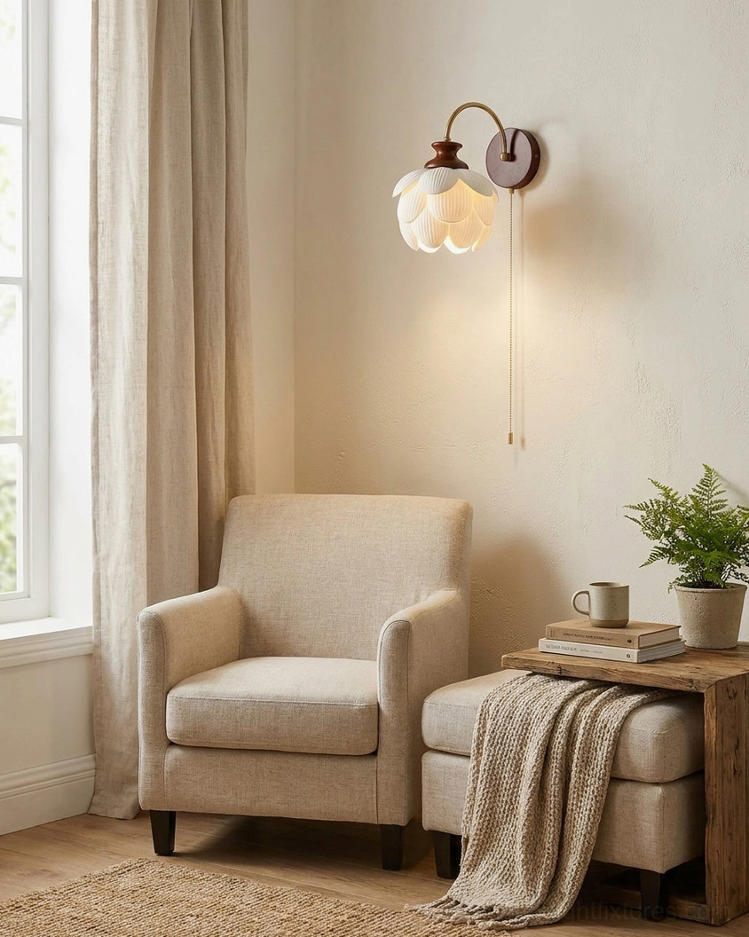 Wall-mounted ceramic flower sconce glowing in living room corner with armchair and warm neutral rustic home decor
