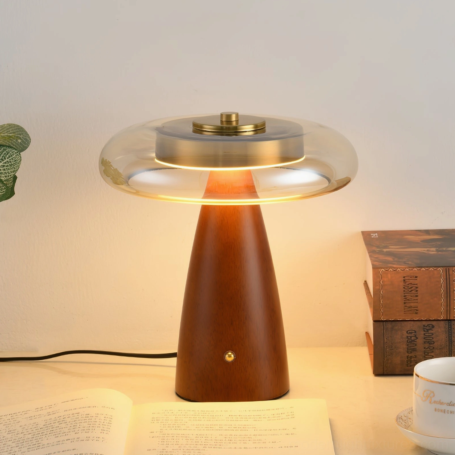 Fathom table lamp styled in home office setting with books and warm ambient lighting from cognac glass shade