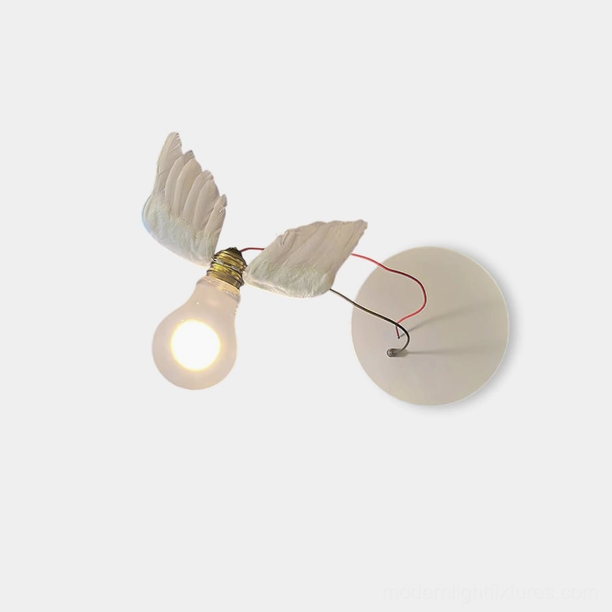 Feathered wing wall sconce with white resin wings and brass accents on white background, front view showing artistic design