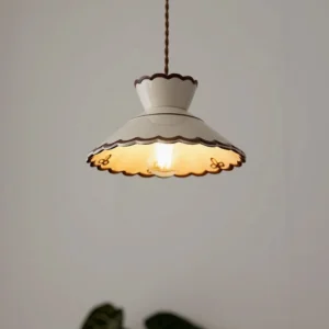 Festonia pendant light hanging with twisted brown cord in warm indoor setting, three-quarter front view showing warm enamel glow
