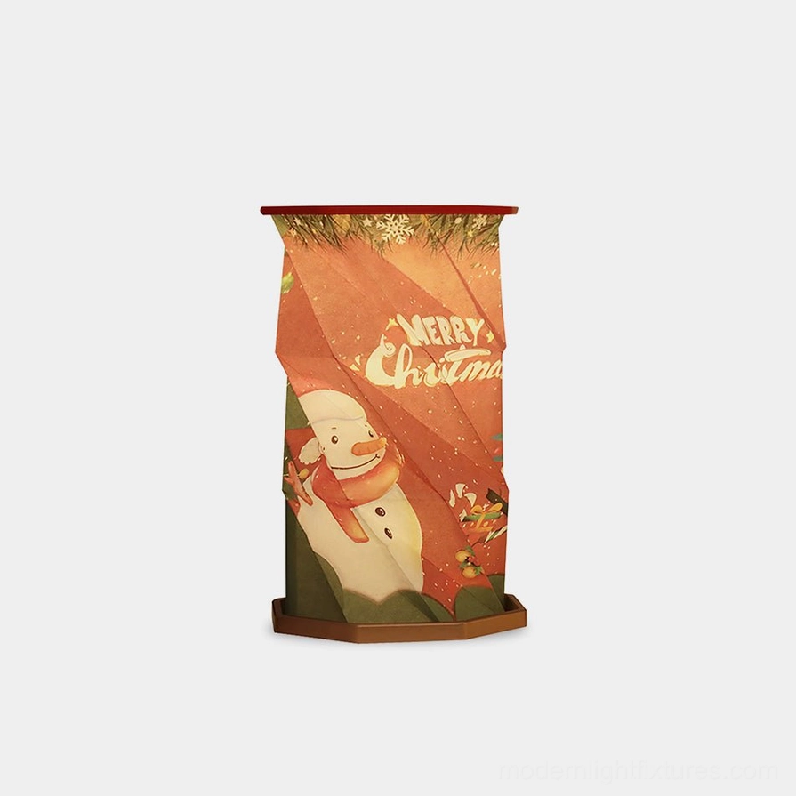 Fida Fold Paper Table Lamp with Christmas snowman print design shown in folded origami cylindrical shape against white studio background