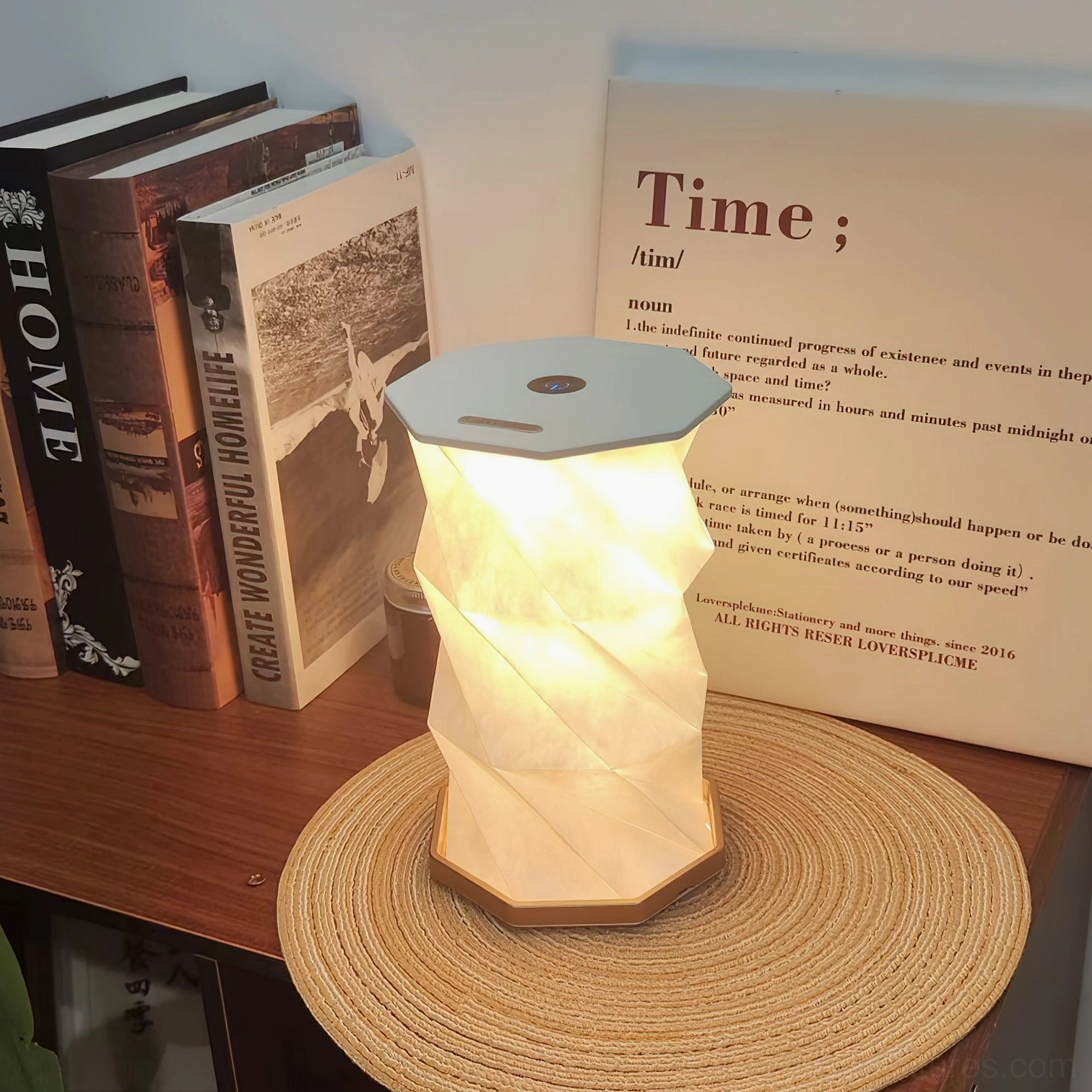 Illuminated Fida Fold Paper Table Lamp with twisted origami shade and warm glow displayed on home office desk with woven placemat