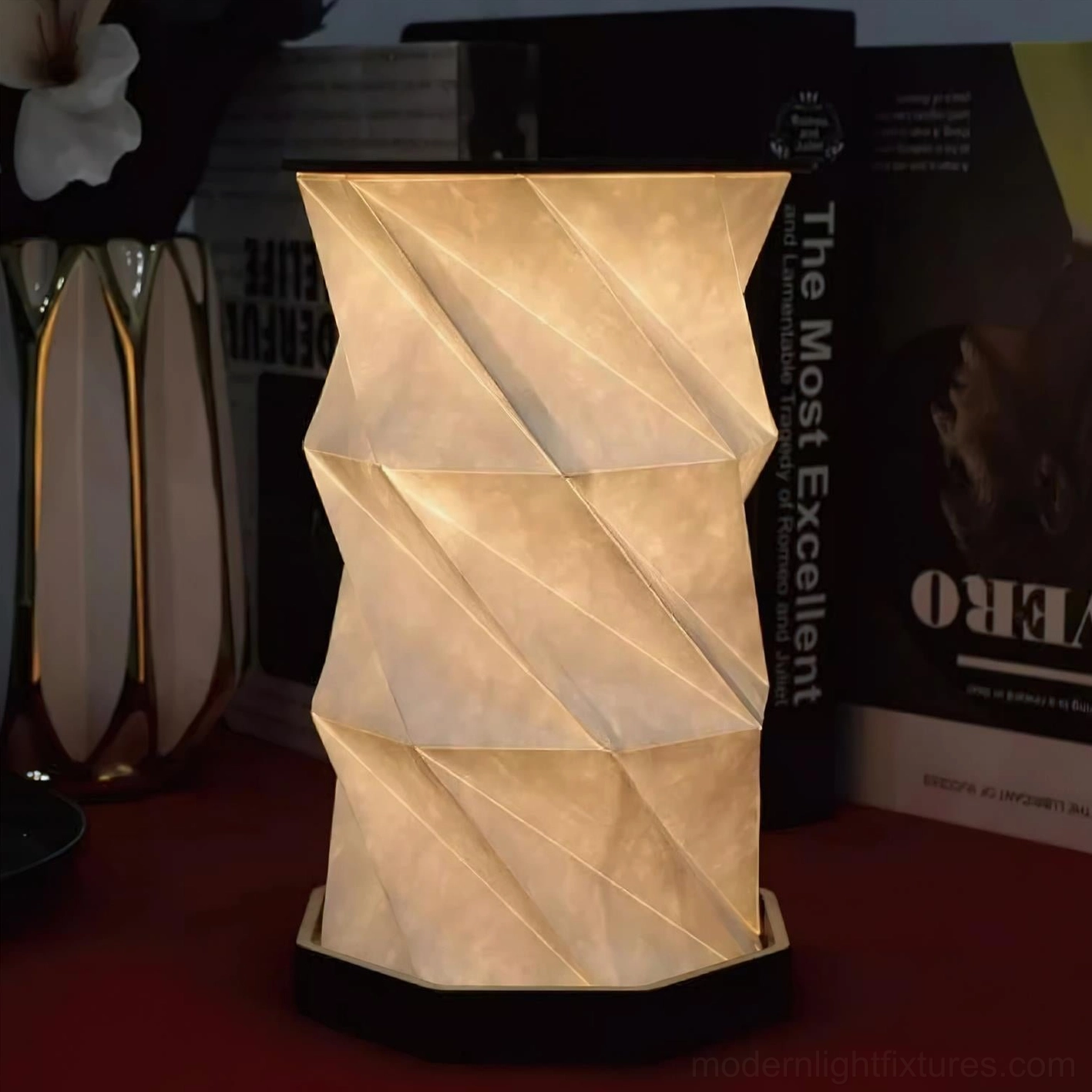 Unlit Fida Fold Paper Table Lamp with solid twisted paper shade and matte black base displayed on reading desk and bookshelf