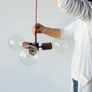 Filotto pendant light with exposed Edison bulb sockets and walnut wood accents in modern home interior, eye-level view