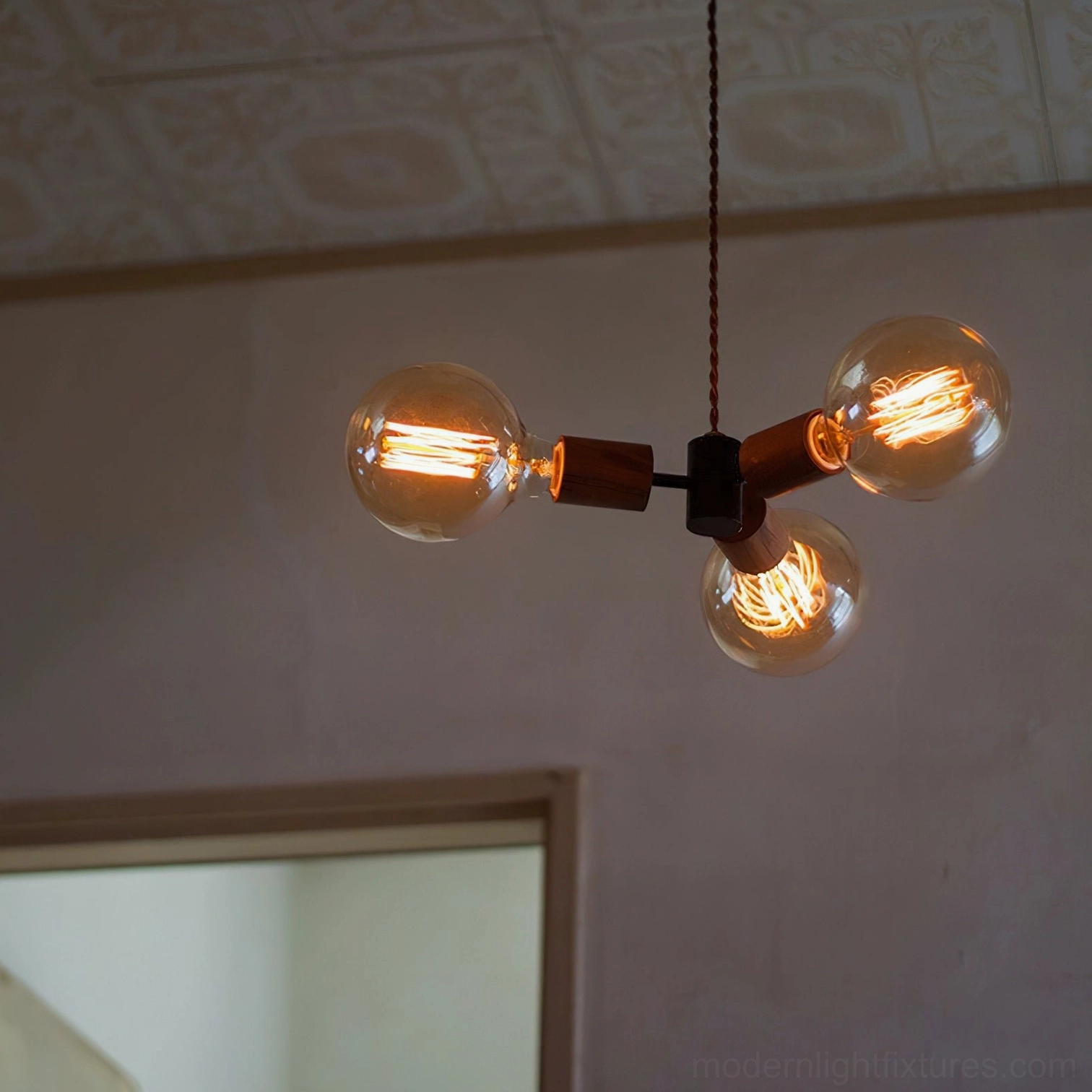 Filotto 3-head pendant with lit warm Edison filament bulbs creating ambient glow in residential living space