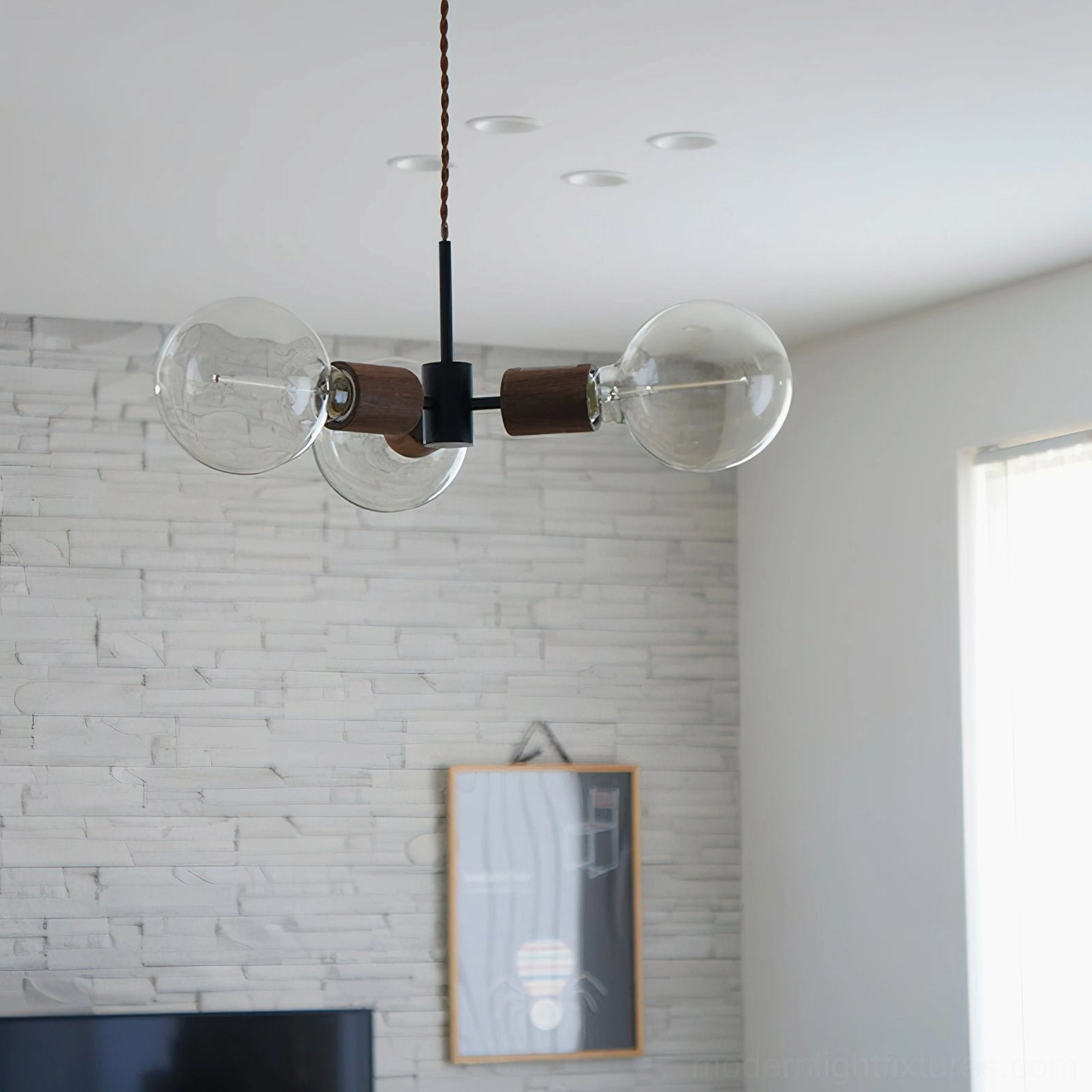 Filotto three-head glass pendant light illuminating modern living room with stone tile wall and minimalist decor