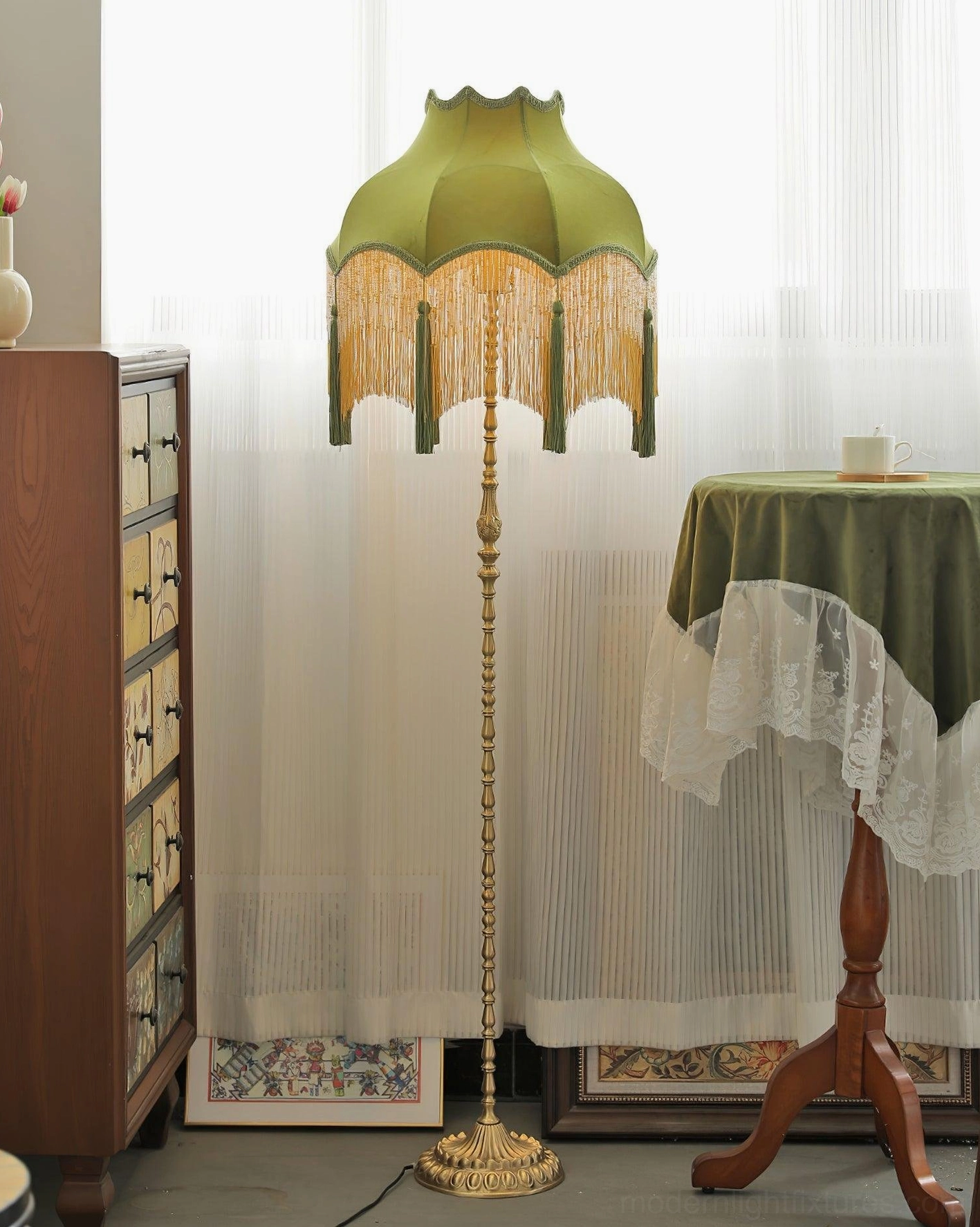 Fina Tassel Floor Lamp standing in sunlit room beside wooden cabinet and side table
