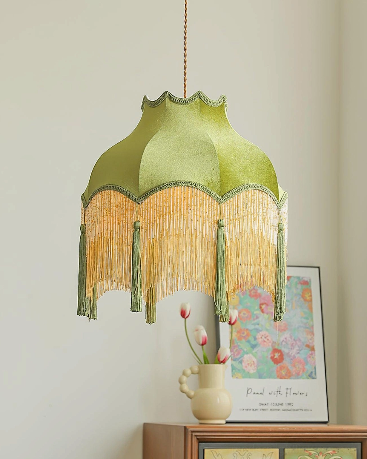 Fina green tassel pendant light close-up with art print and flower vase styling