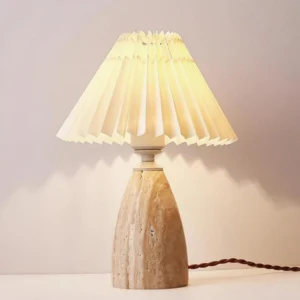 Fina table lamp in modern living room, warm ambient light from pleated shade, brown power cord visible, cozy interior setting