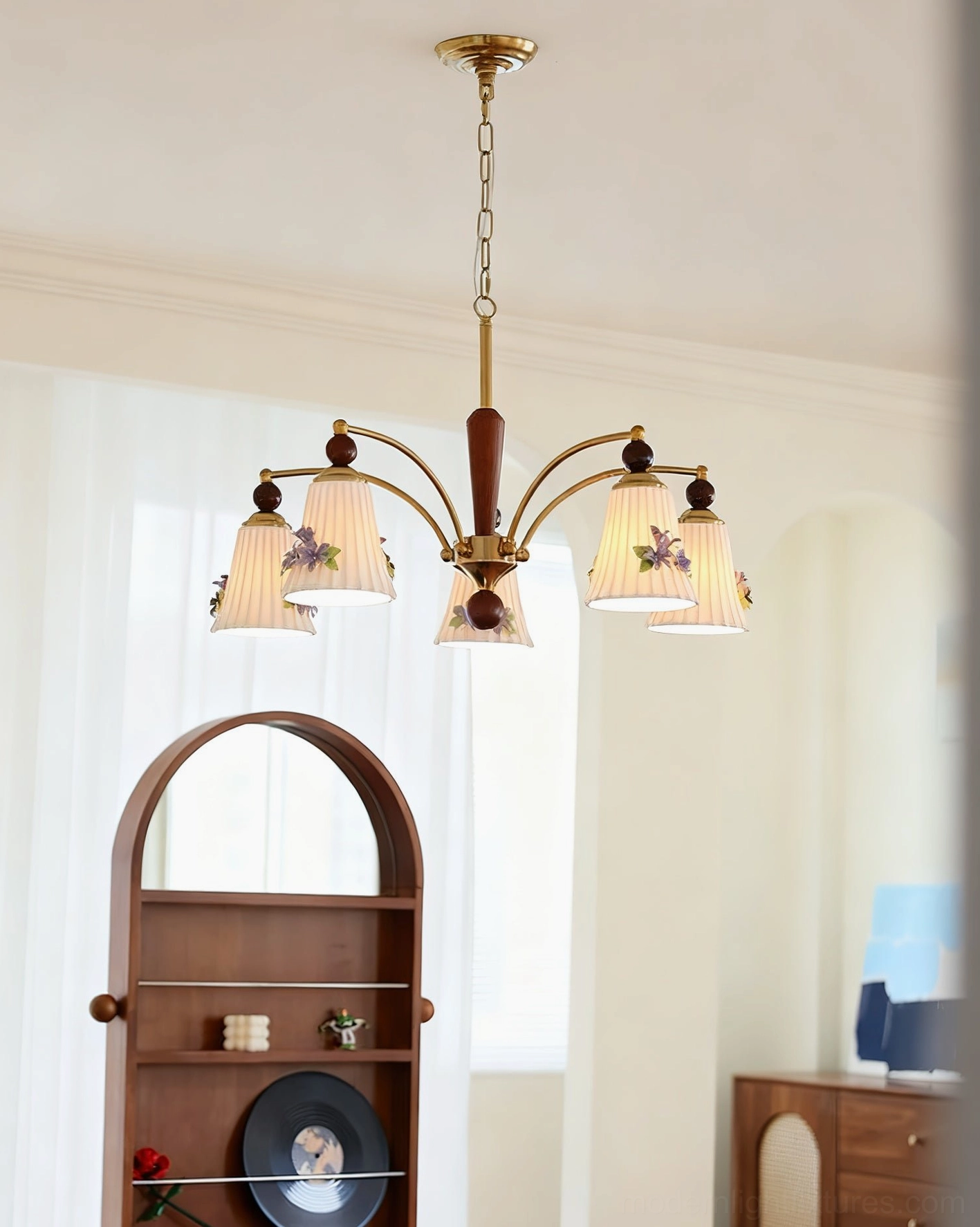 Fiorenta floral chandelier side angle view with brass frame and ceramic shades in living room with arched shelf