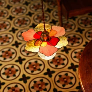Fioria warm amber and red stained glass pendant light hanging in dining room with brass fixture overhead